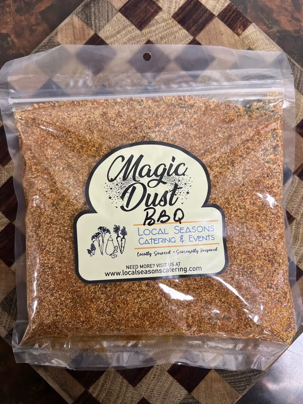 Clear bag of brown Magic Dust BBQ seasoning on a patterned fabric background
