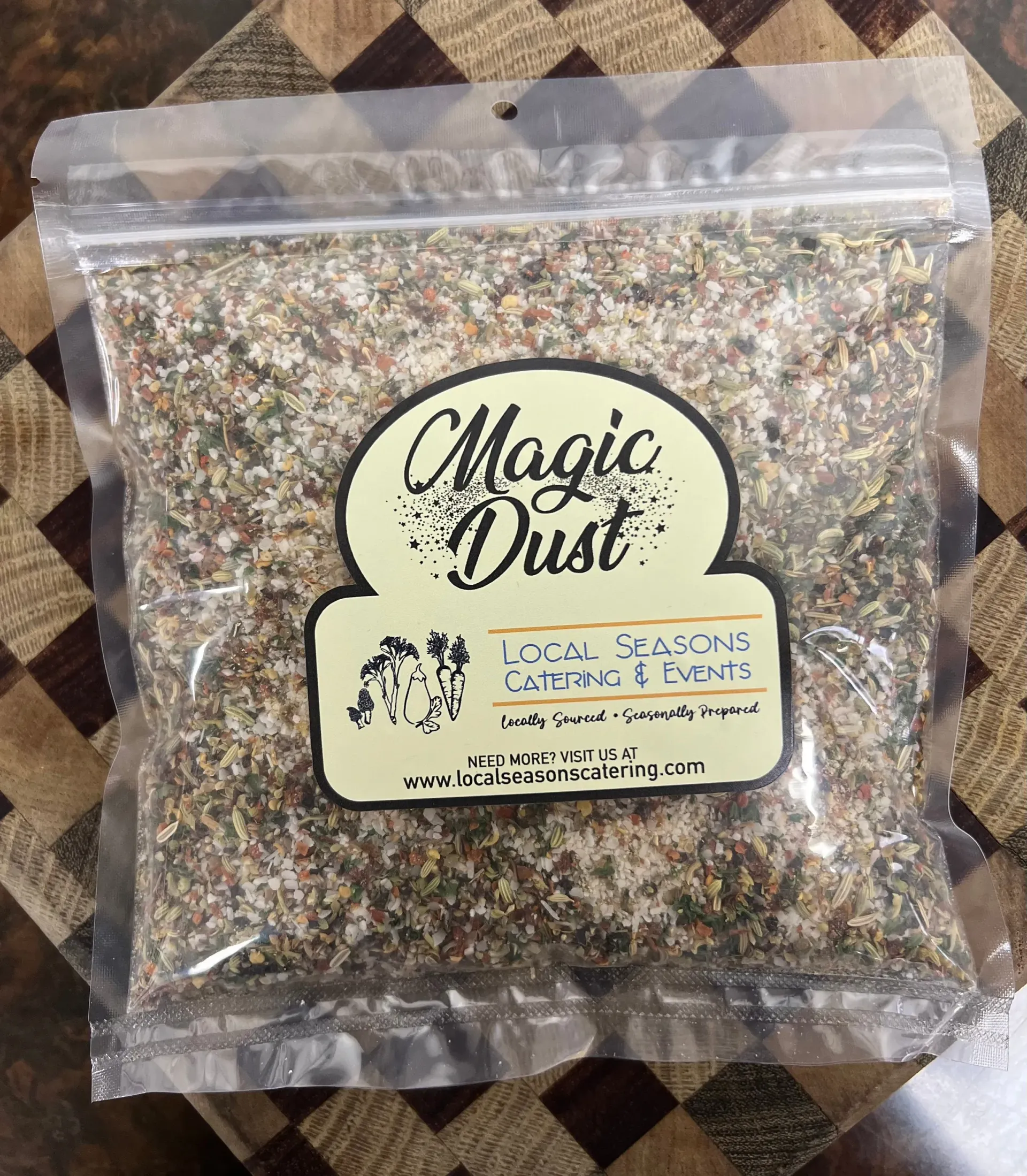 Clear bag of multicolored “Magic Dust” seasoning mix on a patterned tablecloth