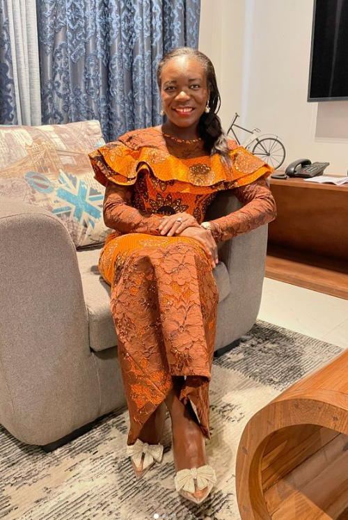 A woman in a dress is sitting on a couch in a living room.