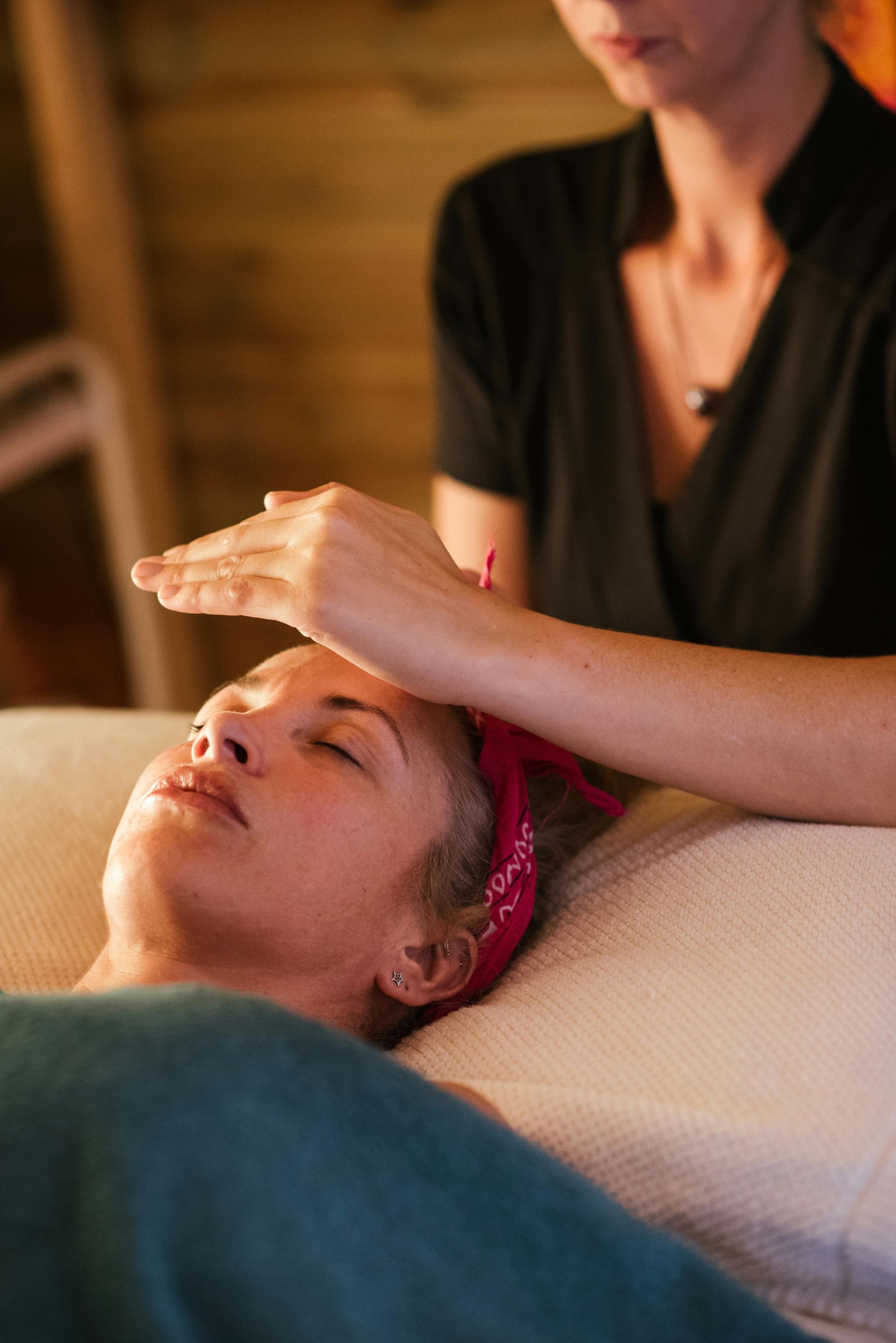 A woman is laying on a bed getting a massage from a woman.