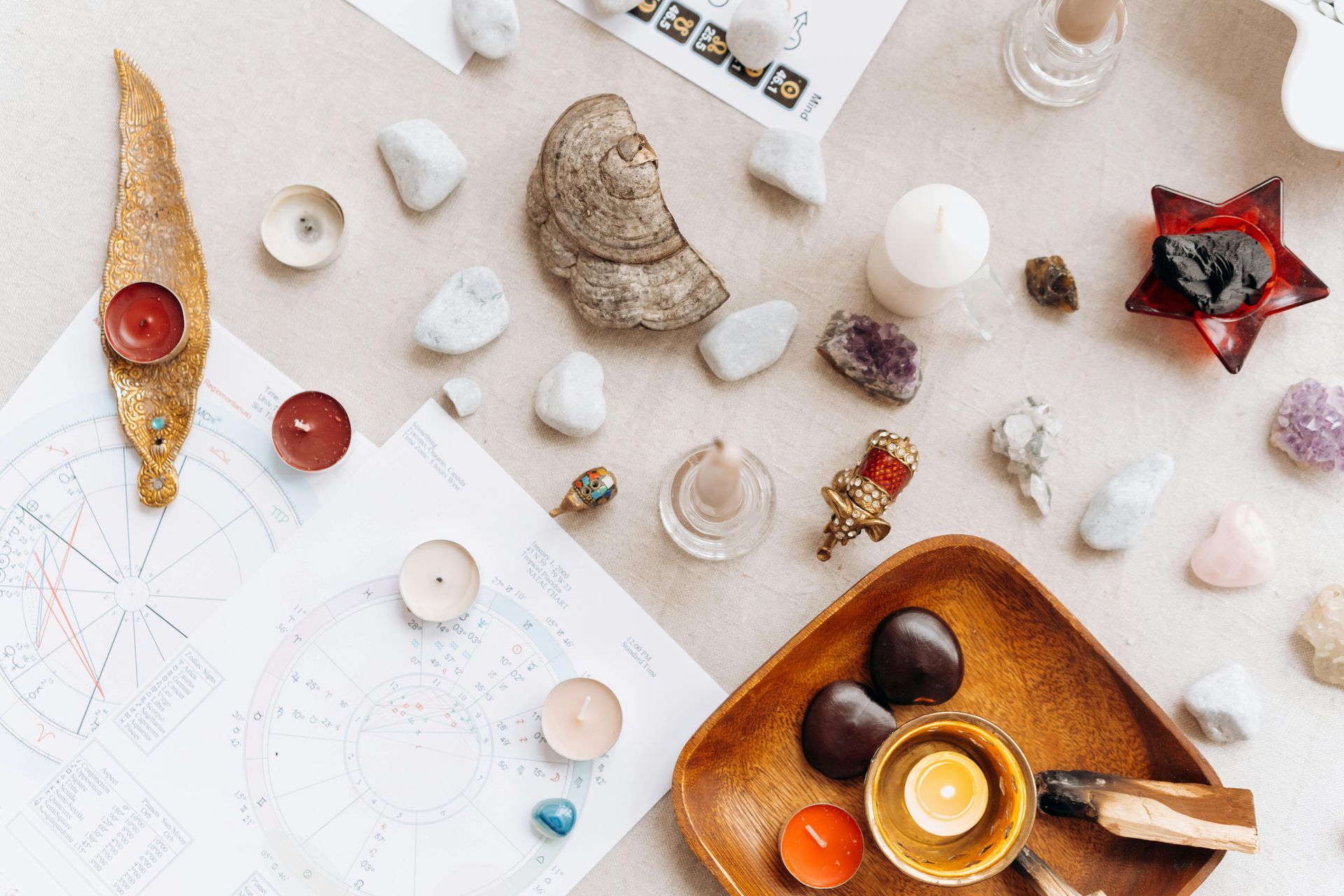 A wooden tray filled with candles , rocks , and stones on a table.