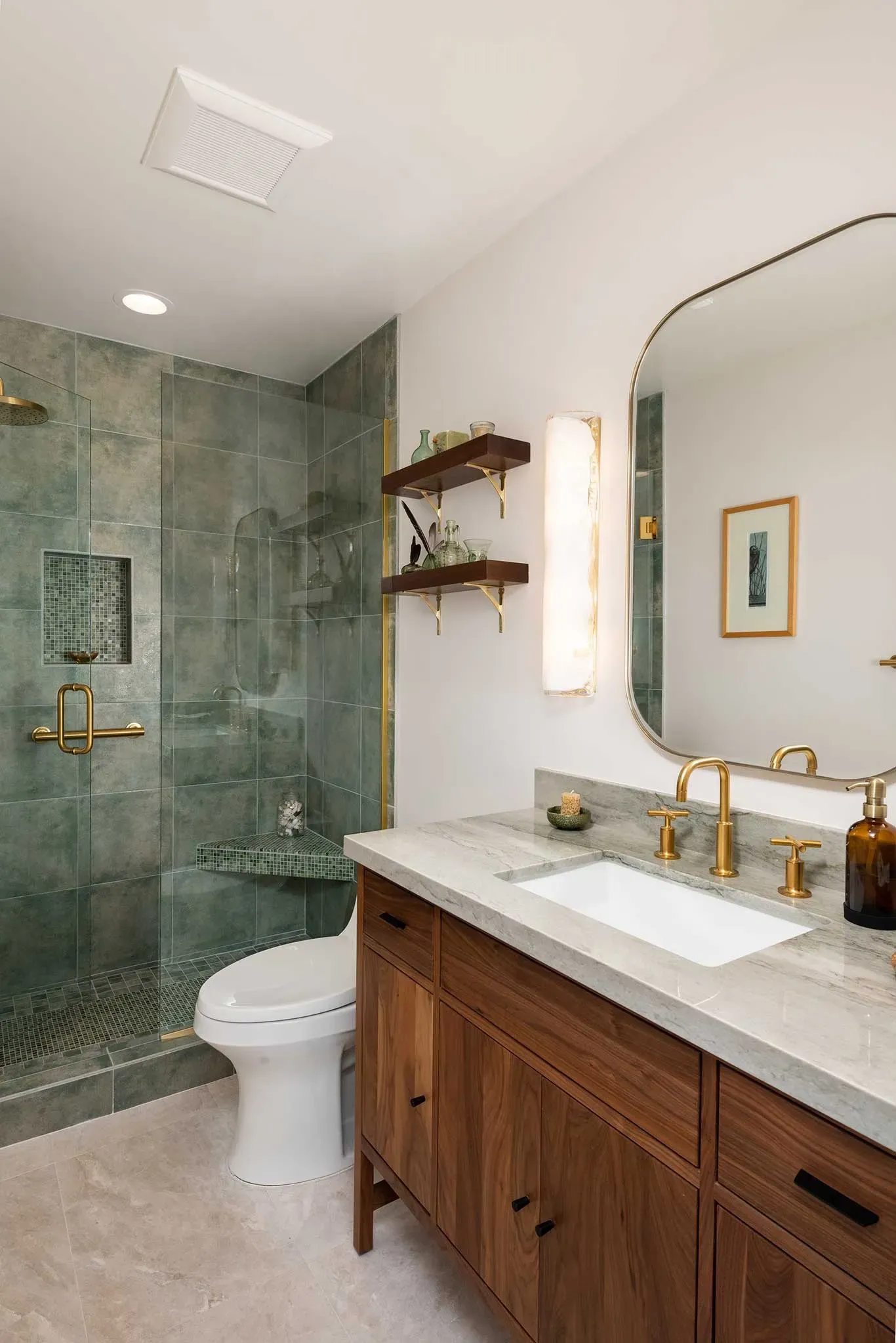 A bathroom with a toilet , sink , mirror and walk in shower.