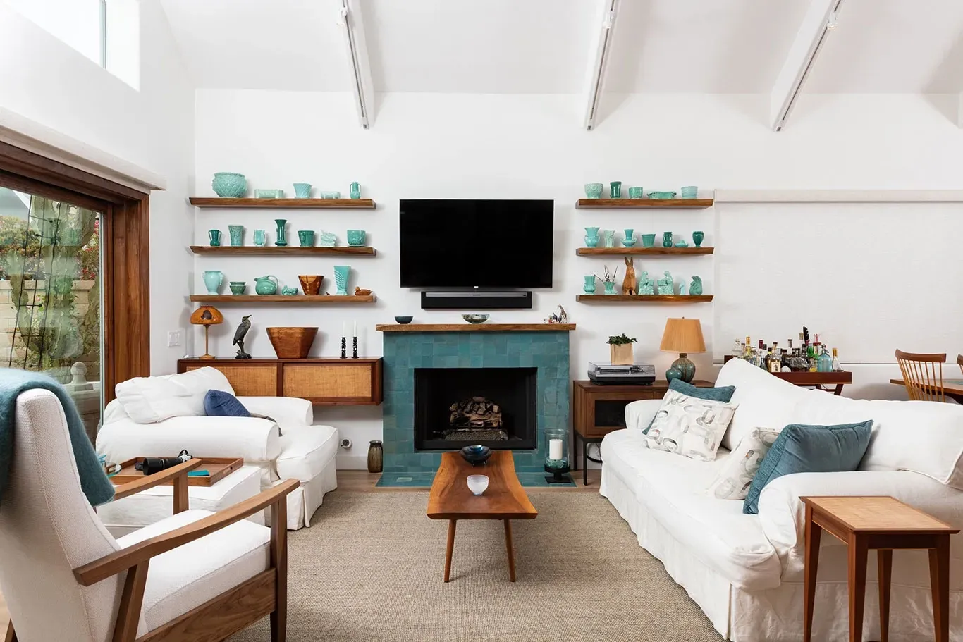 A living room with a couch , chairs , a fireplace and a flat screen tv.