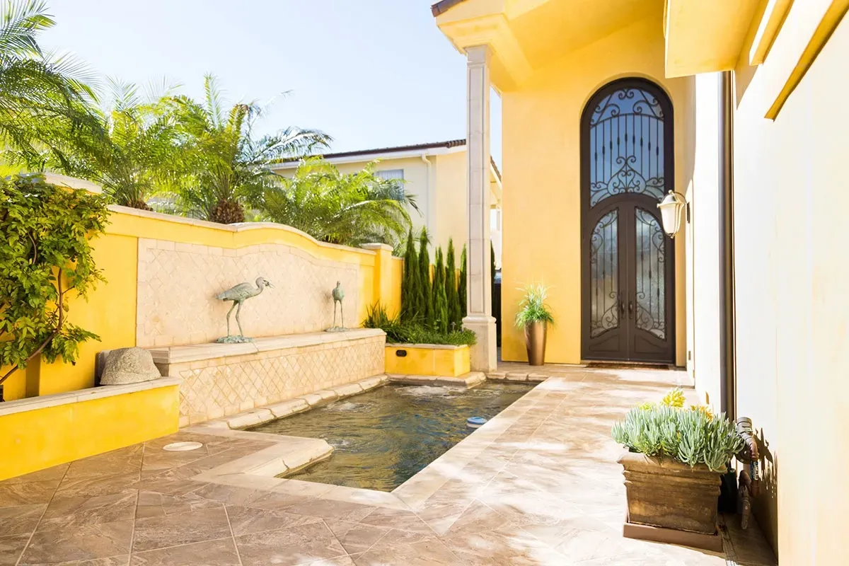 A large yellow house with a pool in front of it.