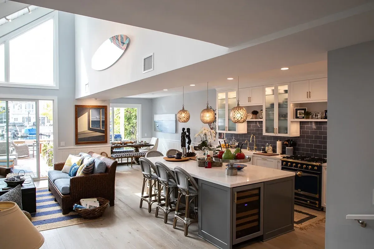 A living room and kitchen in a house with a large island in the middle.
