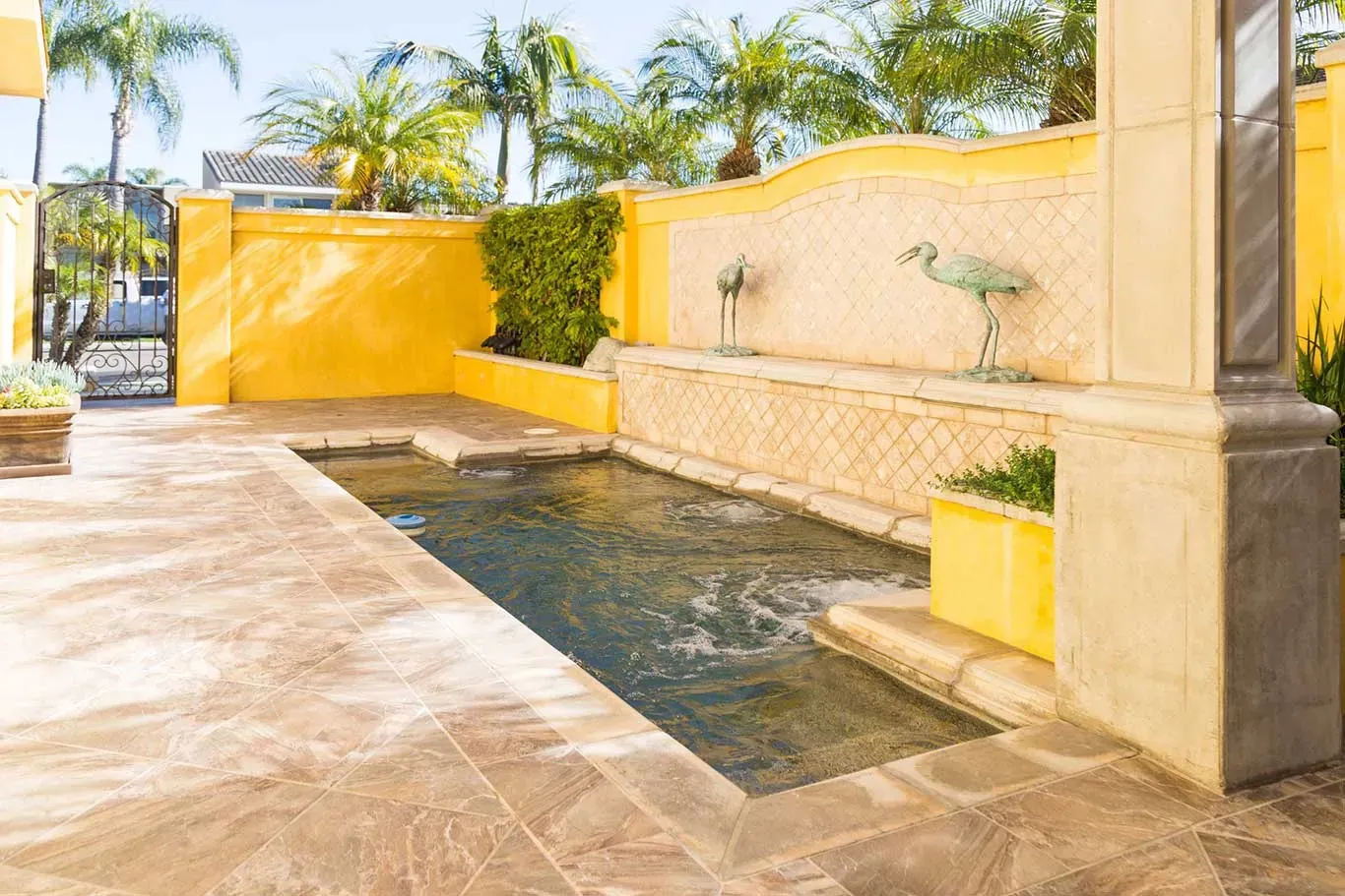 A swimming pool with a fountain in the backyard of a house.