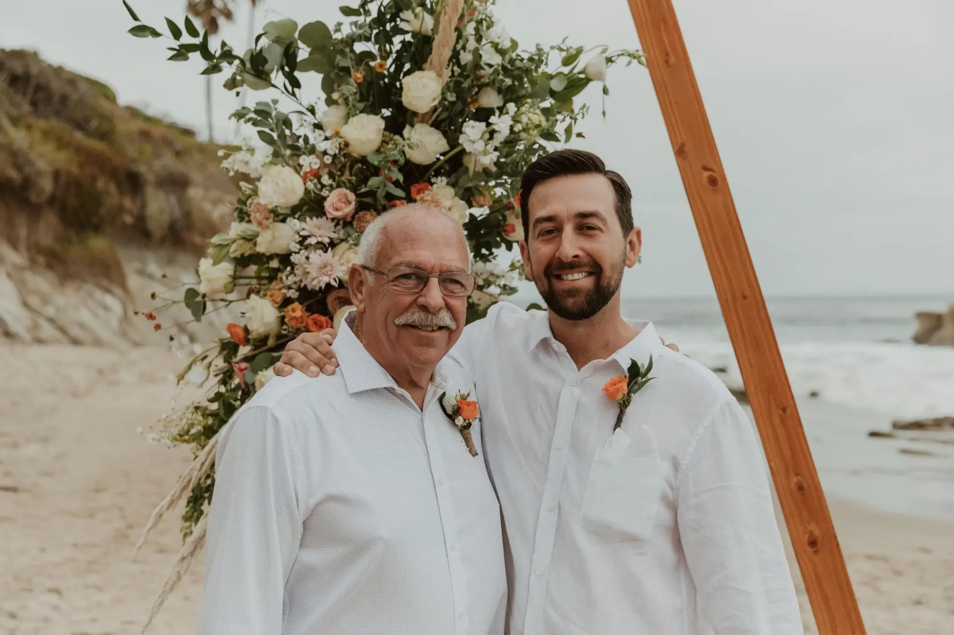A bride and groom are posing for a picture on the beach.