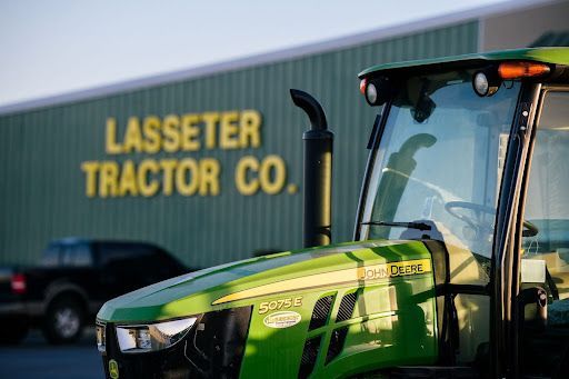 A green tractor is parked in front of a building that says lasseter tractor co.