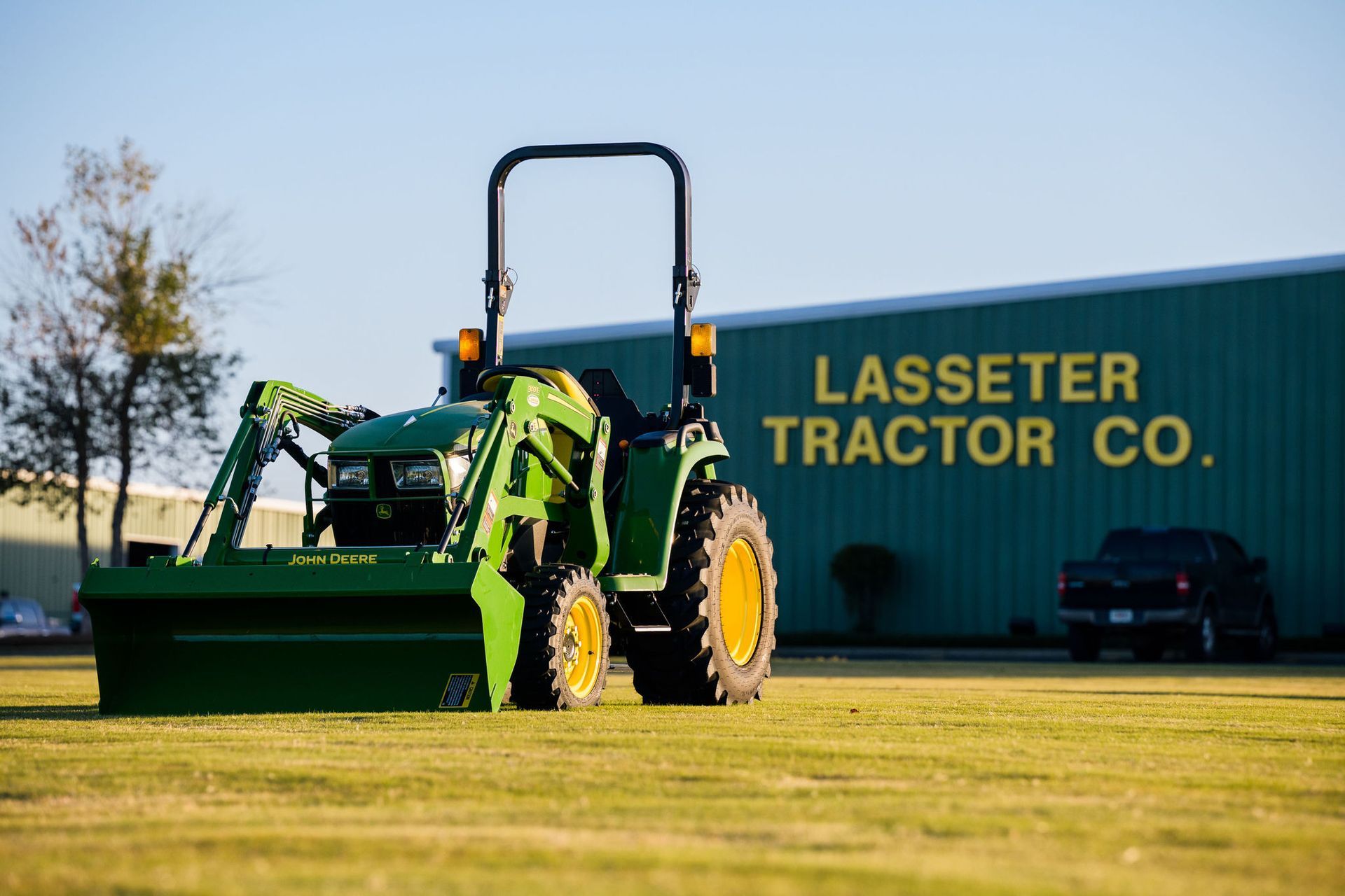 A green tractor is parked in front of a building that says lasseter tractor co.