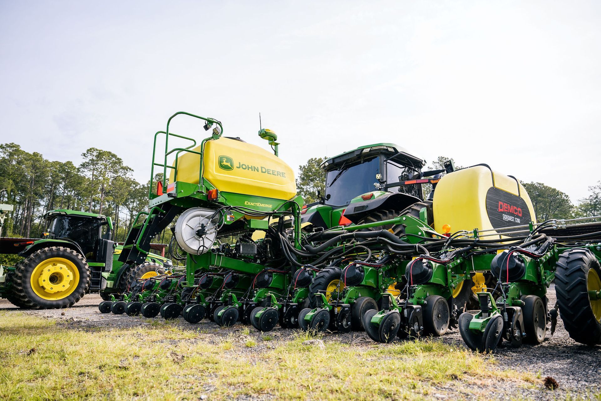 A john deere tractor is parked next to a planter in a field.