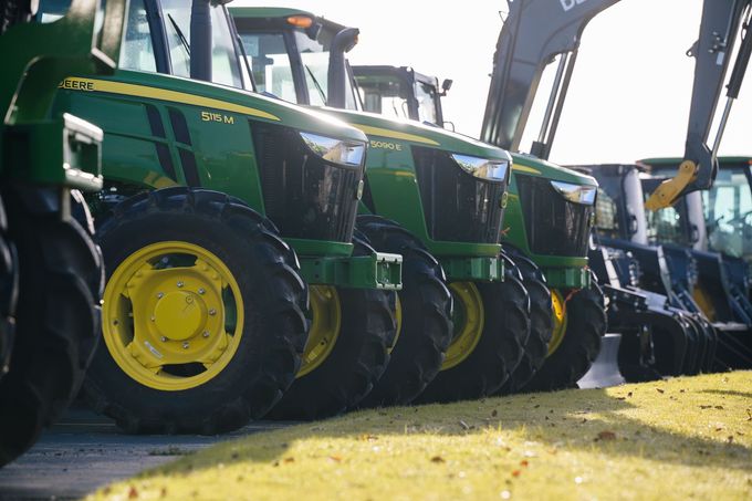 A row of green and yellow John Deere tractors are parked next to each other.