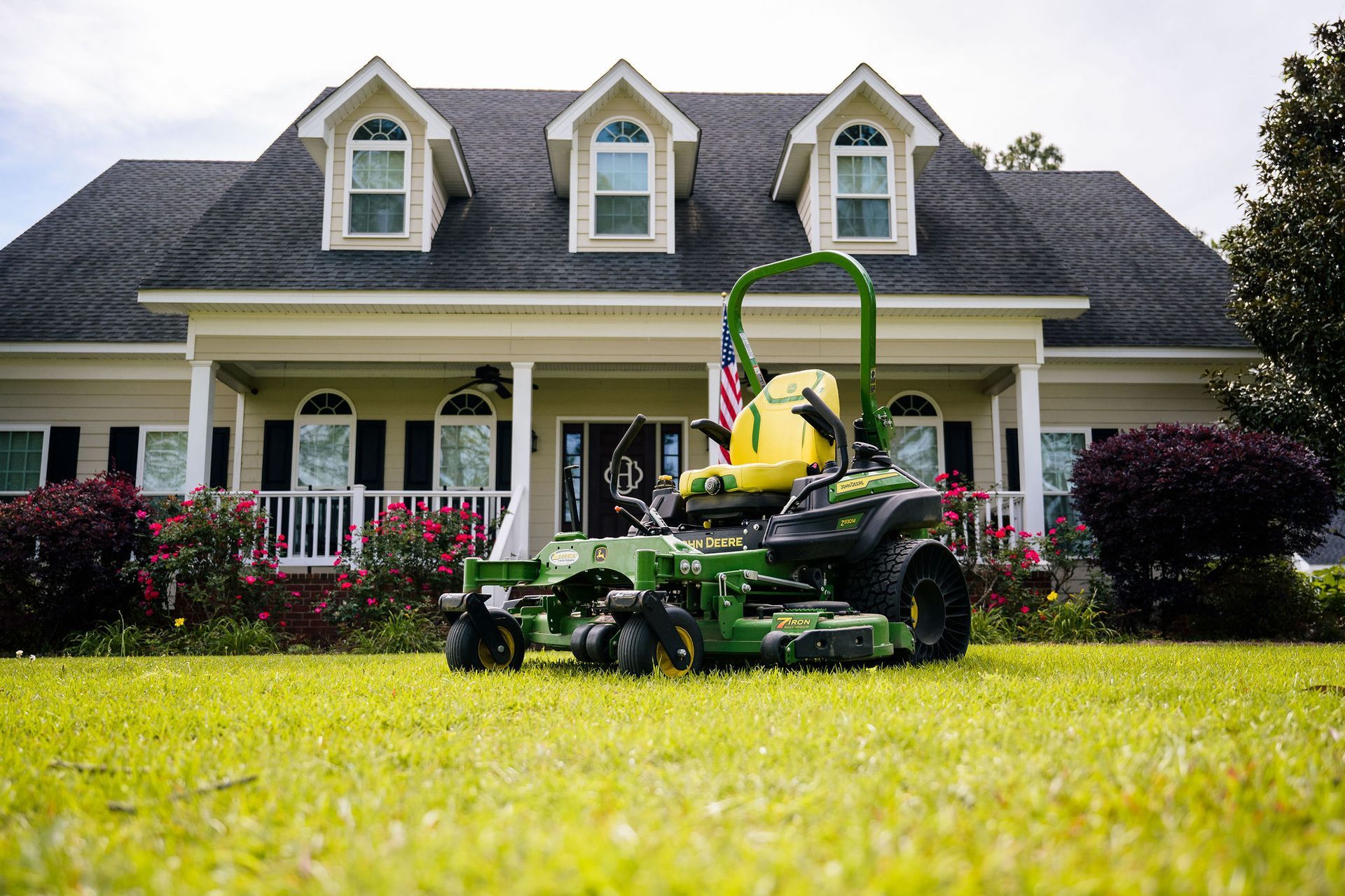 A man is riding a John Deere lawn tractor on a lush green field.