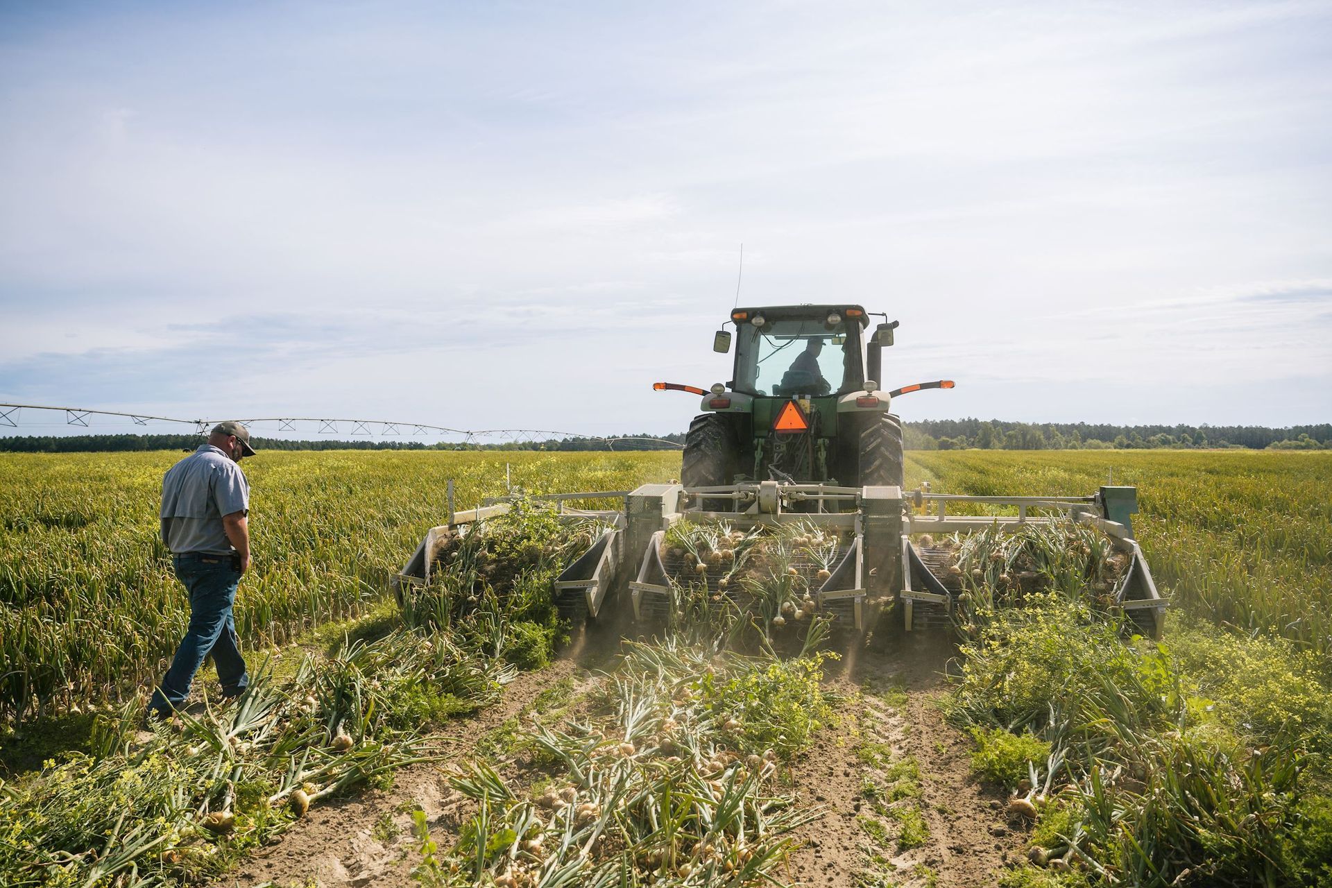 A man is walking in a field with a tractor in the background.