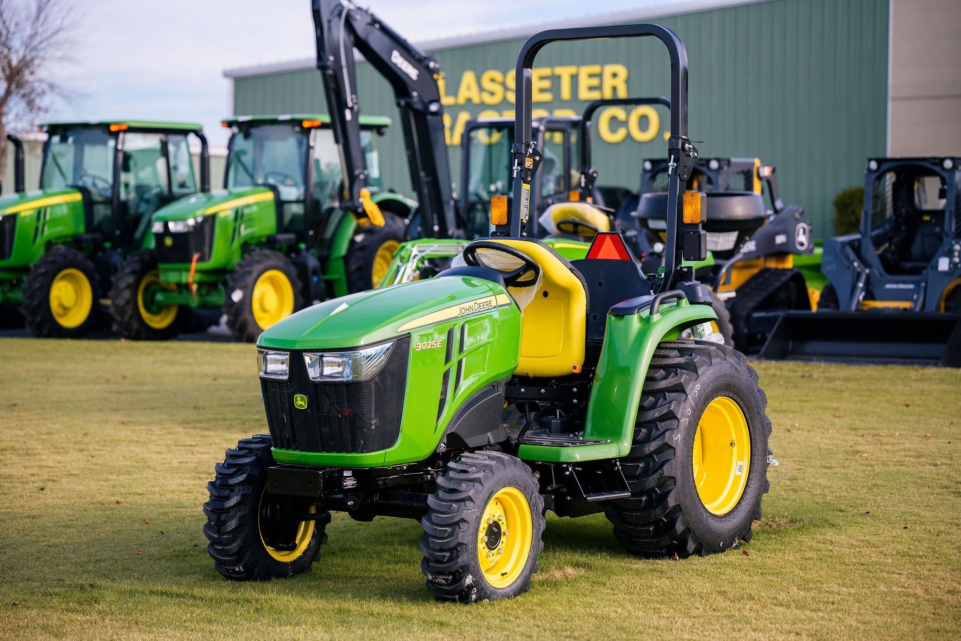 A green and yellow john deere 3025e tractor is parked in front of a building.
