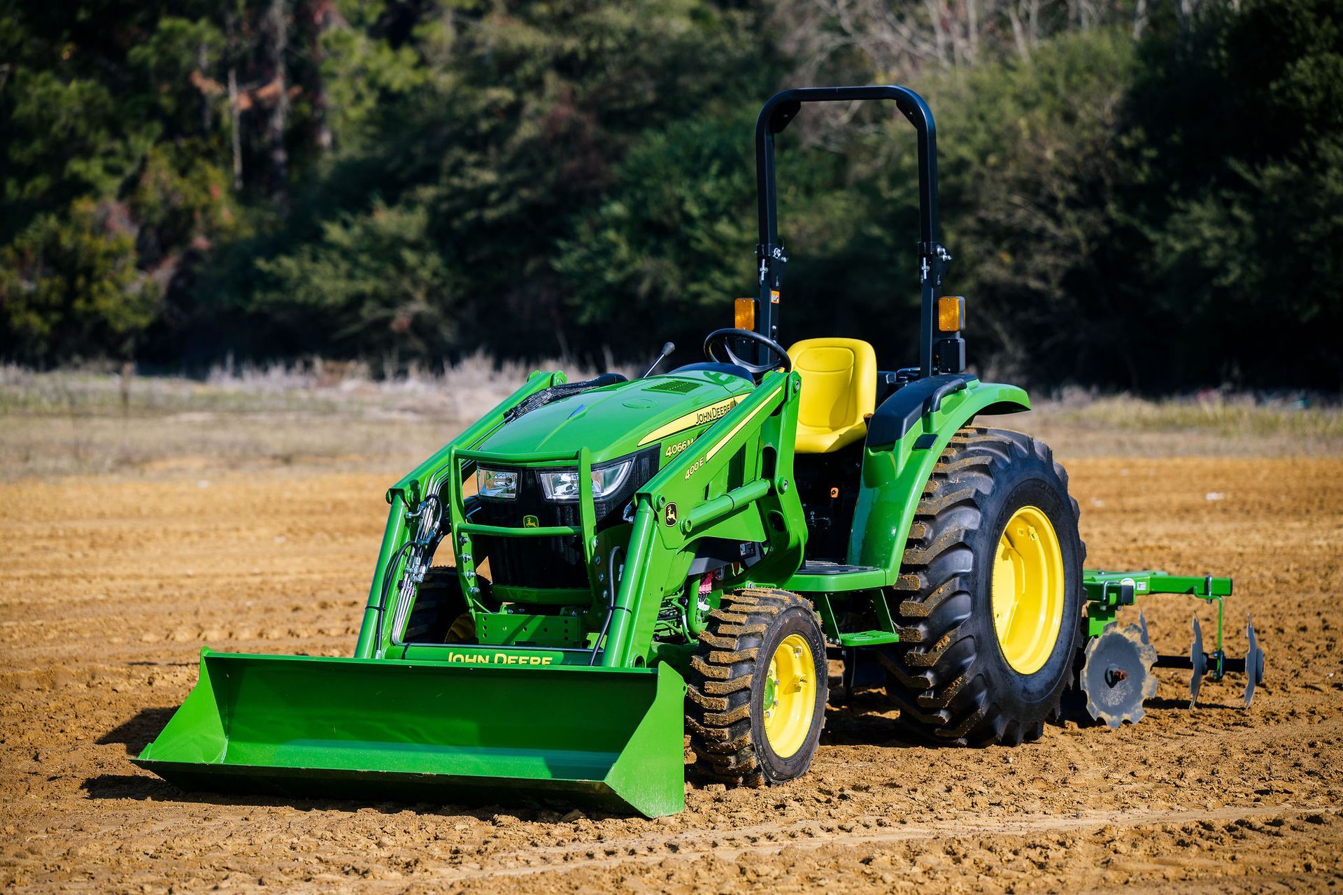 A green john deere 4066m tractor is plowing a field.