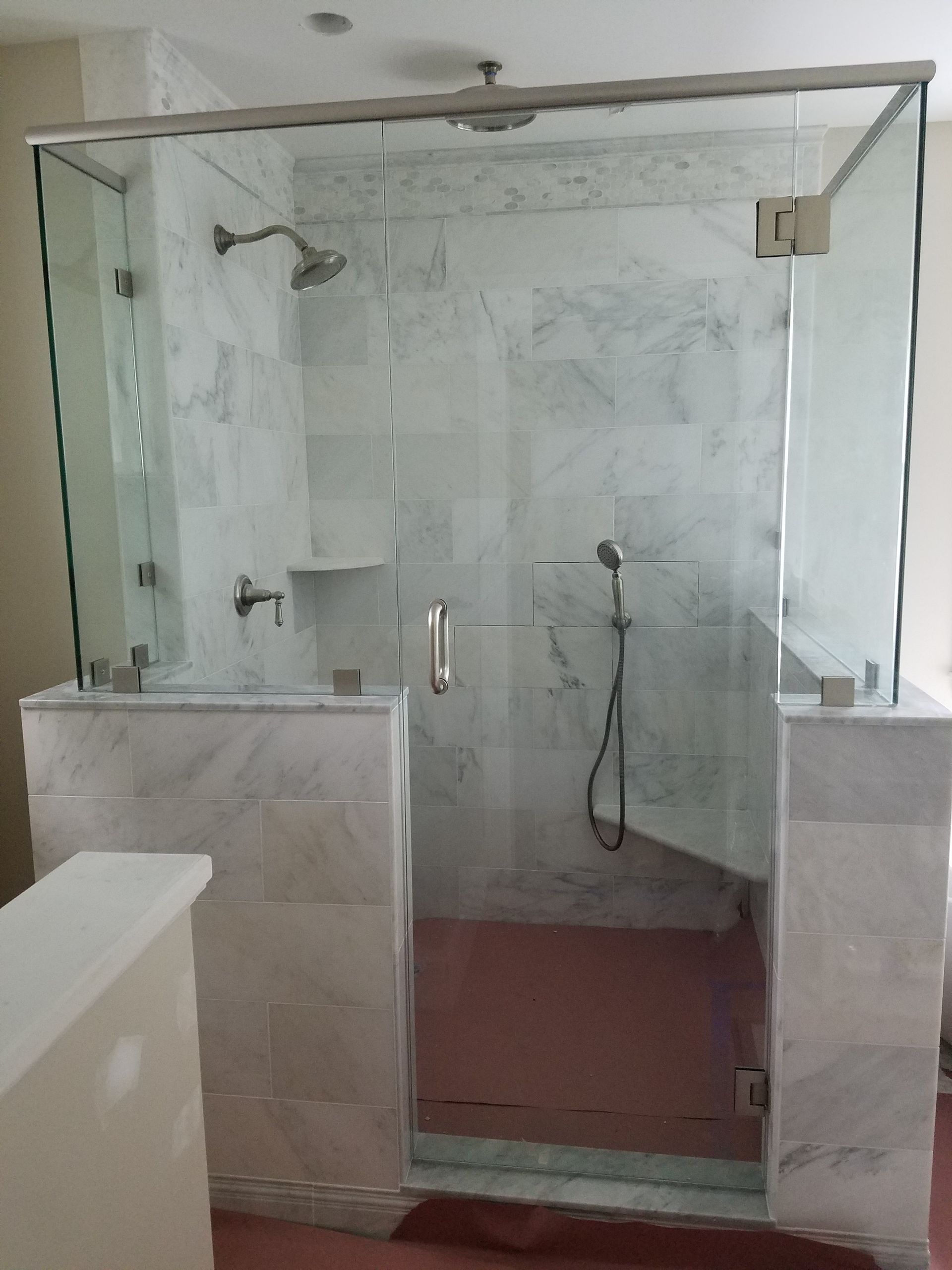 A bathroom with a walk in shower with a glass door.
