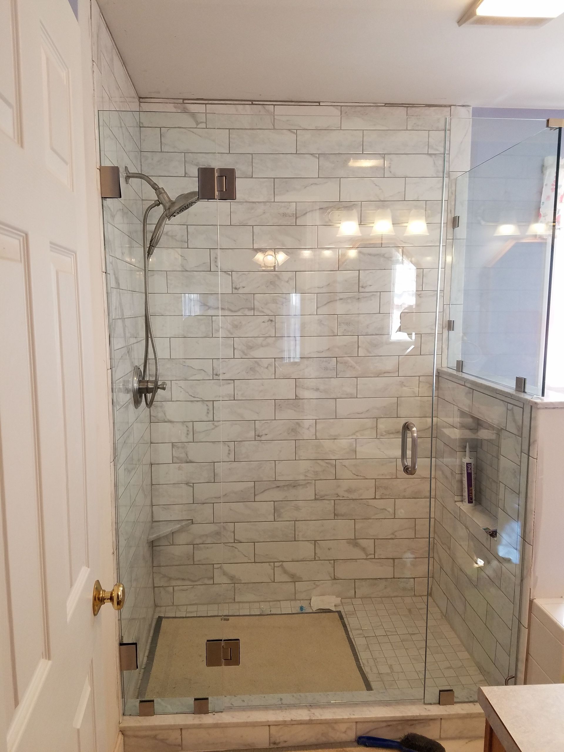 A bathroom with a walk in shower with a glass door