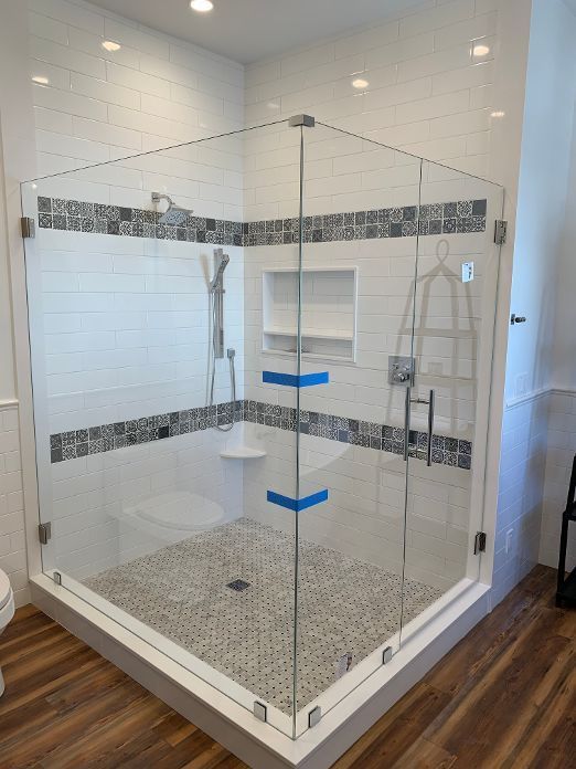 A bathroom with a walk in shower with a glass door.