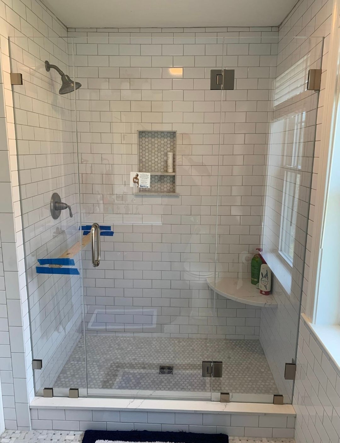 A bathroom with a walk in shower with a glass door.