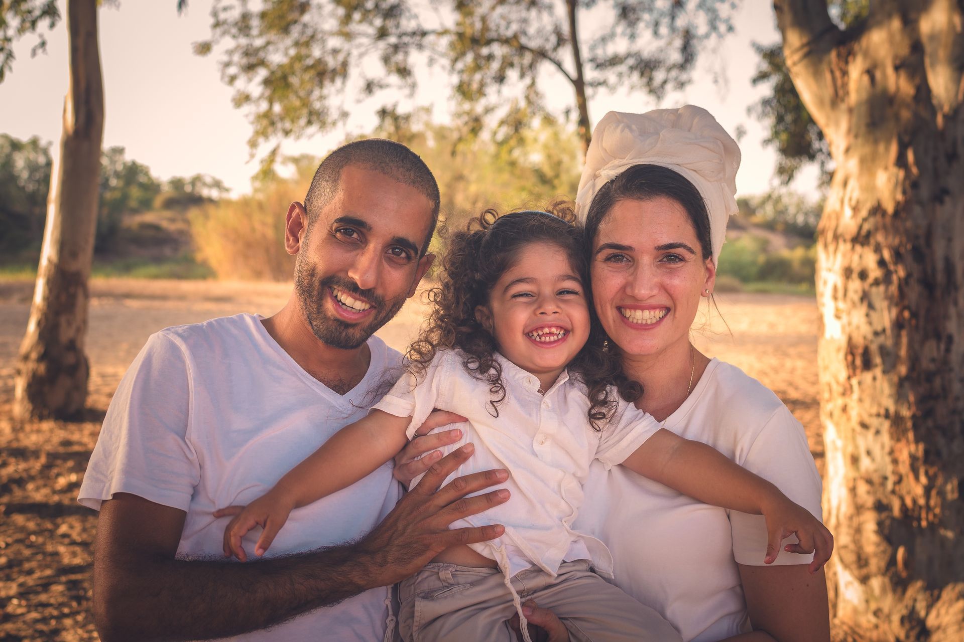 הורים אוחזים ילד בן 3 שמביט למצלמה