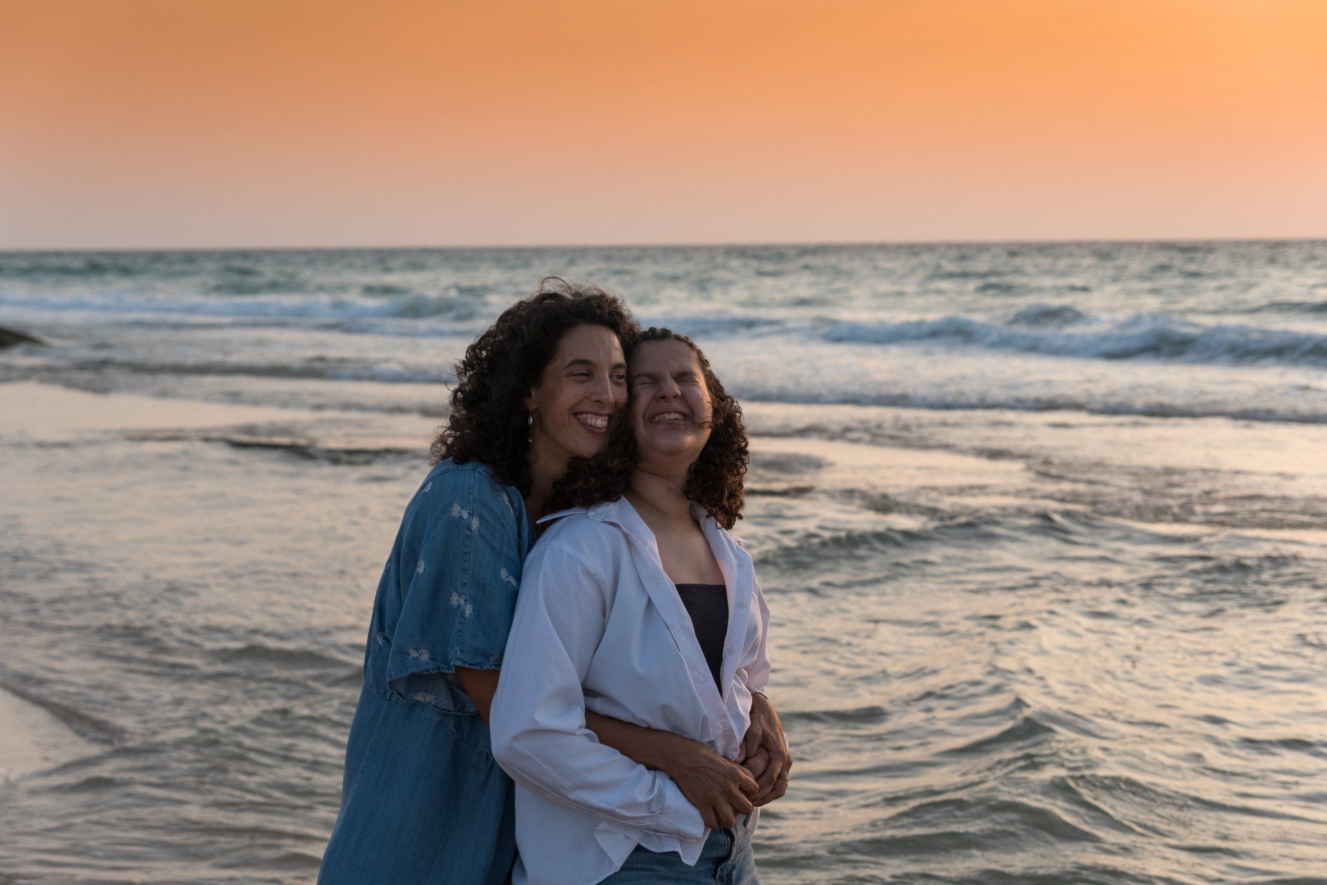 אמא ובת מחובקות על רקע הים בצילומי משפחה בטבע