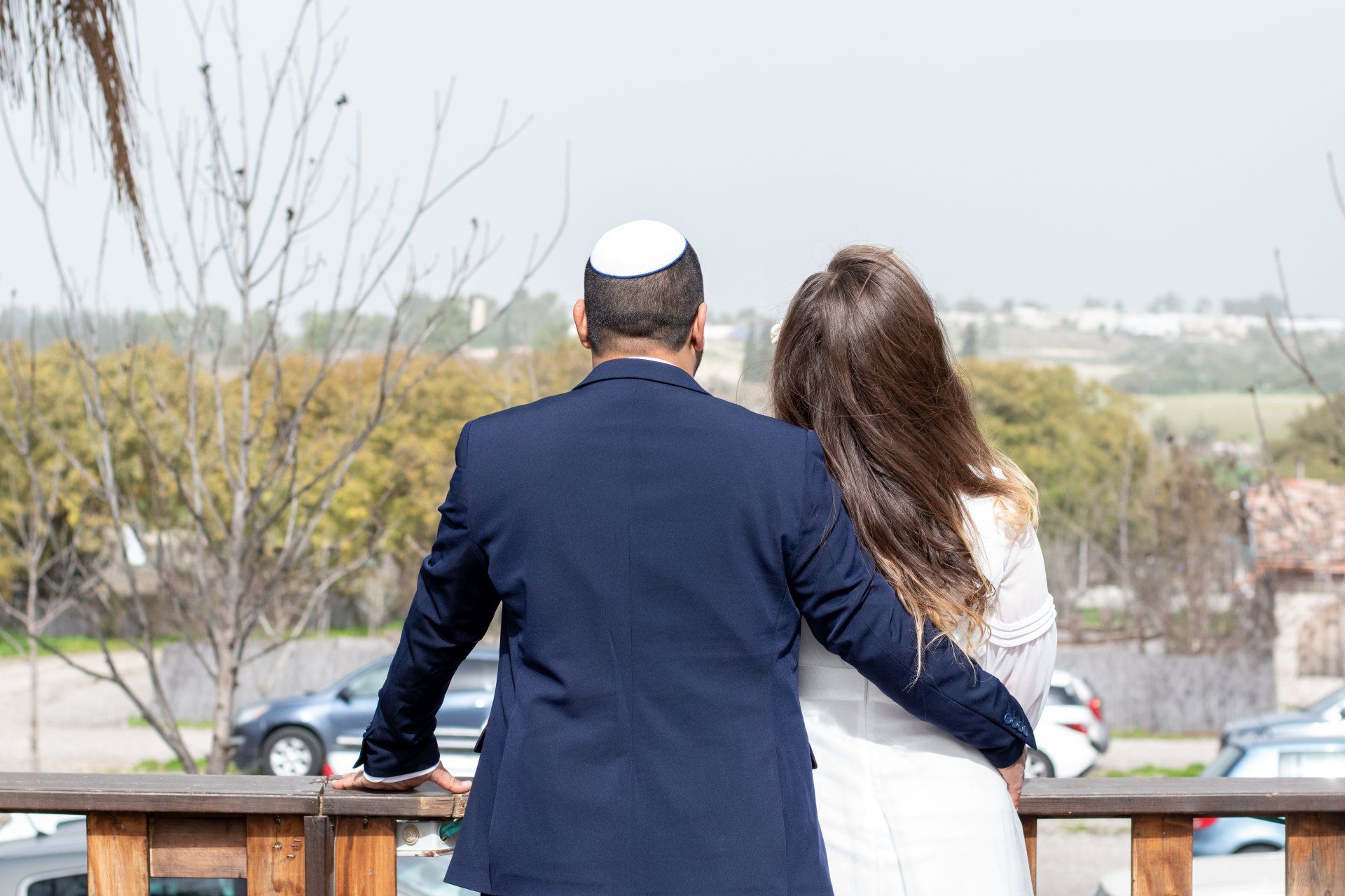 חתן וכלה בגבם למצלמה ופניהם לעתיד משותף ושמח