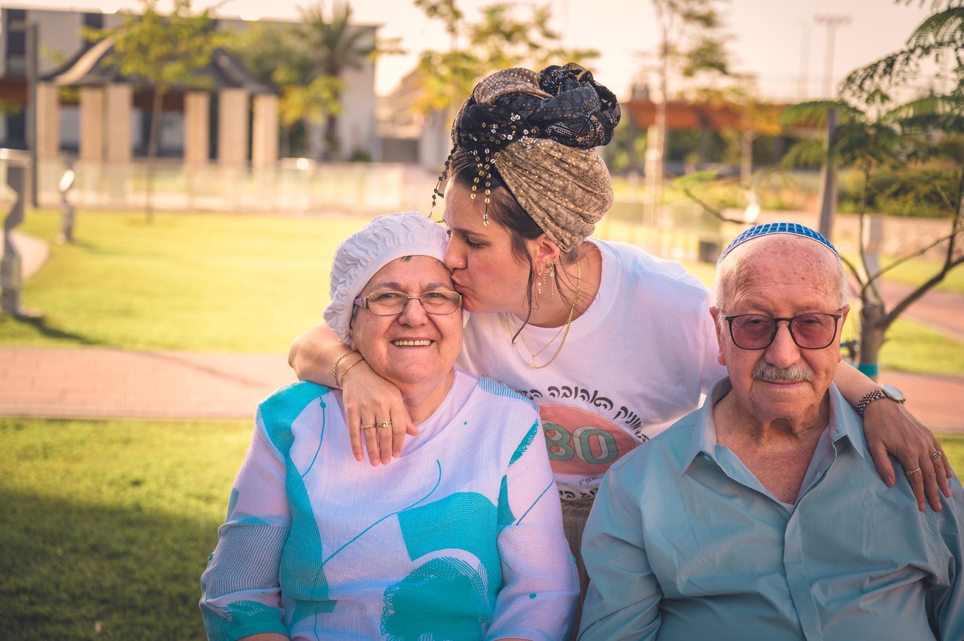 אשה מנשקת את אמא המבוגרת לצד אביה המבוגר בצילום משפחתי
