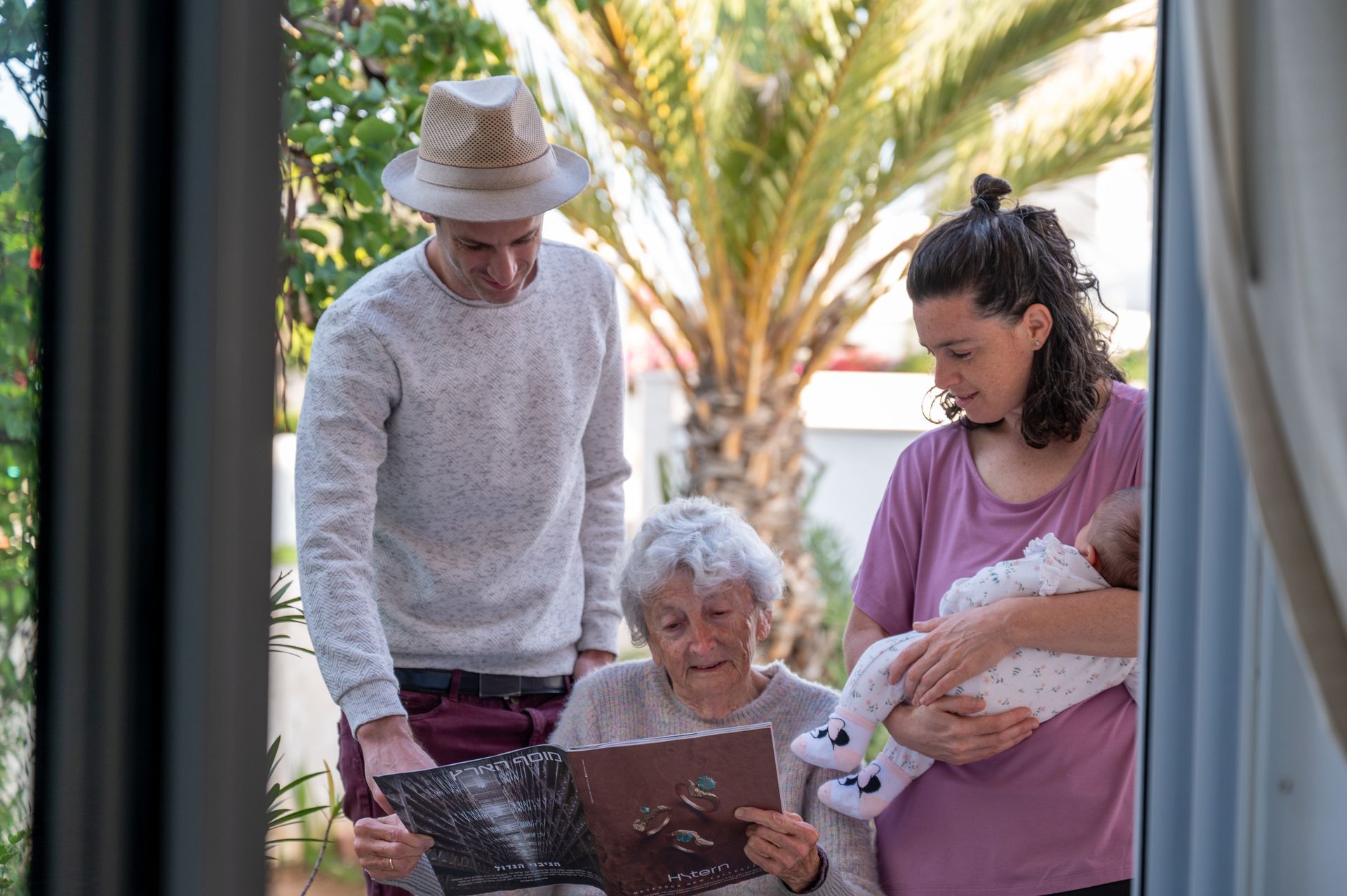 סבתא נכדים ונינה חדשה מביטים בעיתון בצילומי משפחה