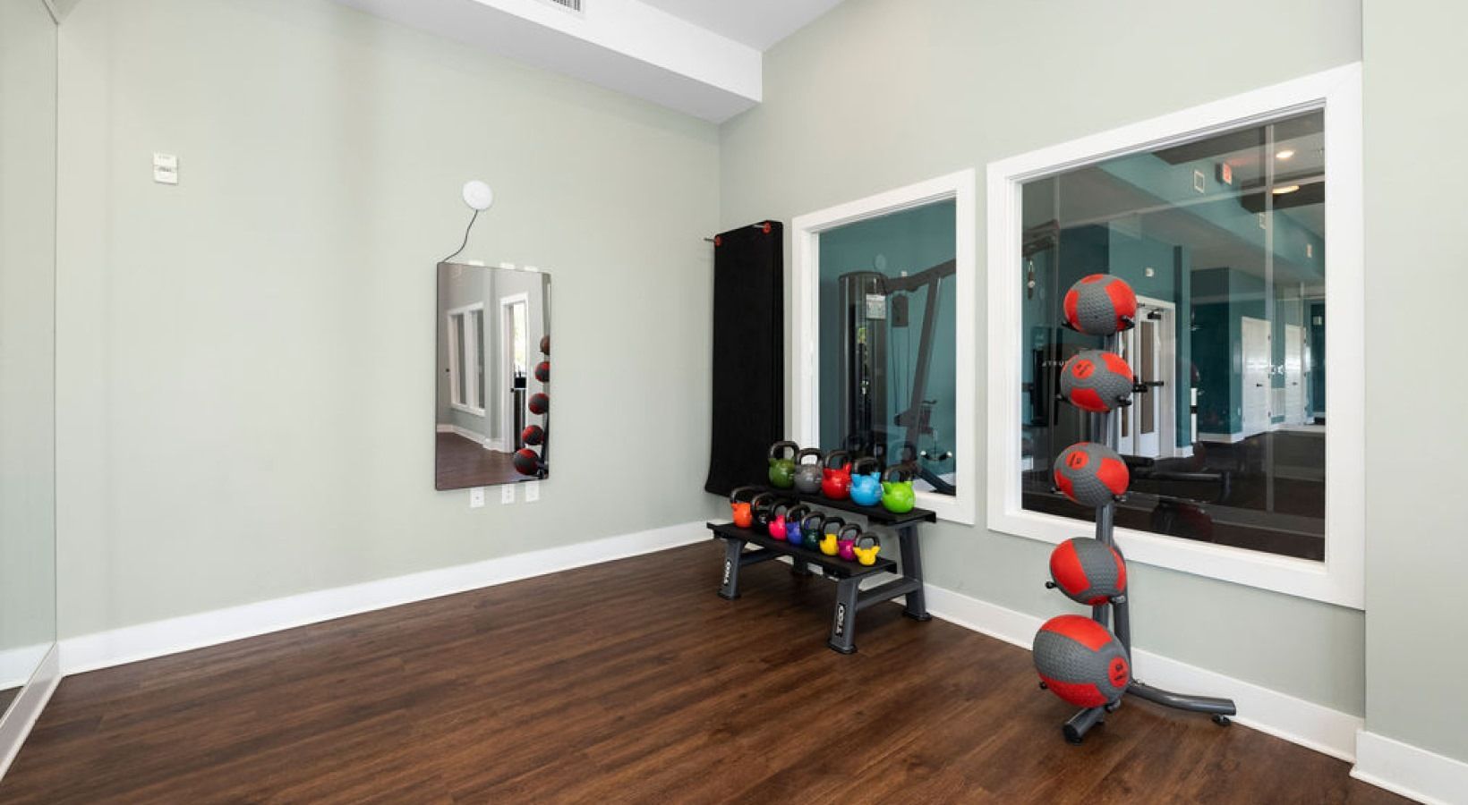 Small gym area with free weights, kettlebells, and a mirror wall.