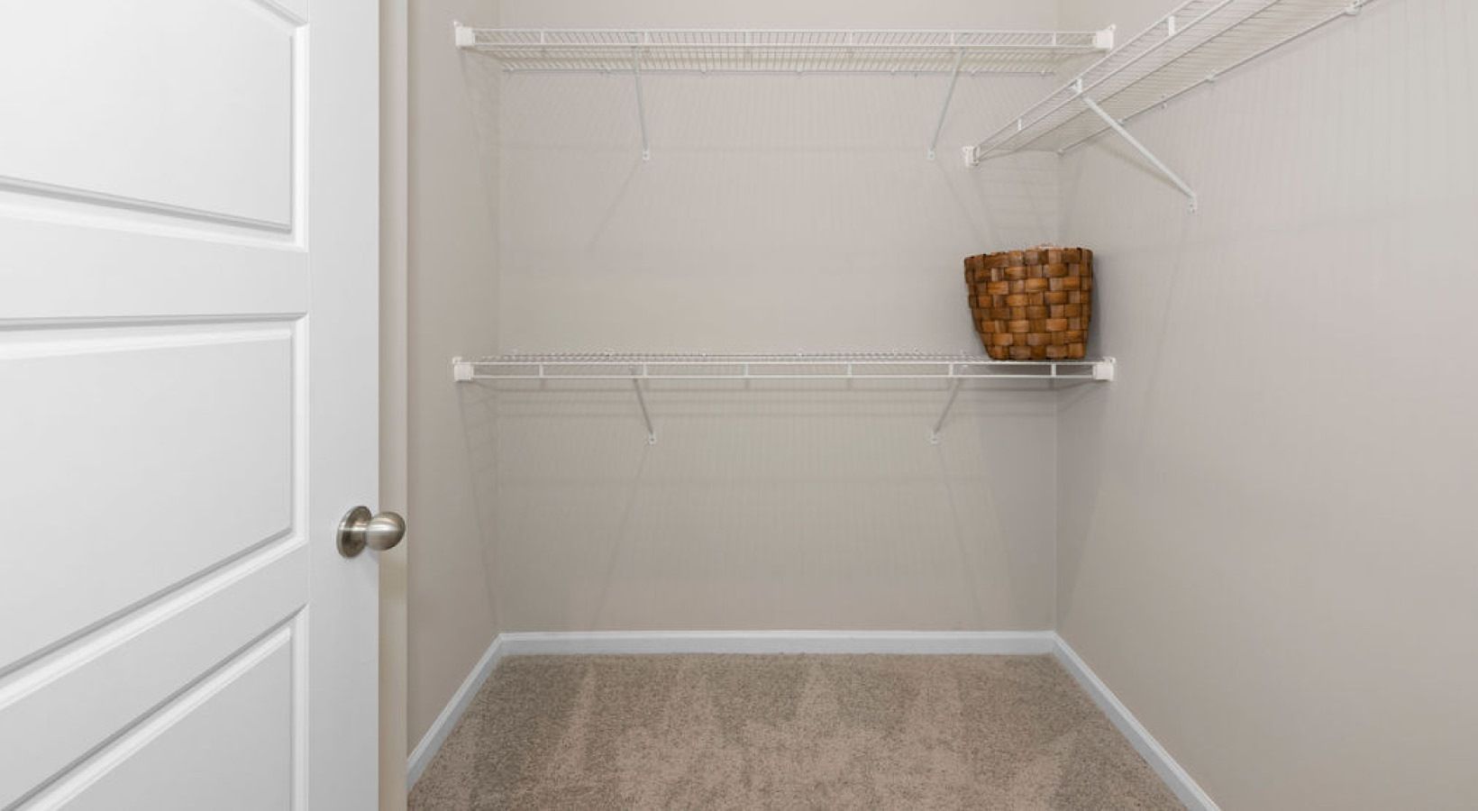 Walk-in closet with white wire shelves and a woven basket.