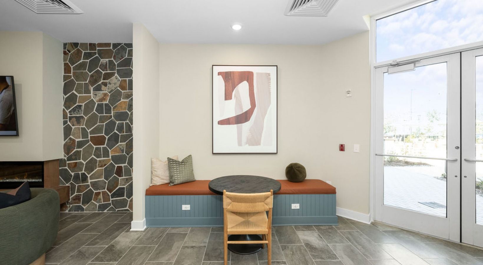Lobby seating area with a built-in bench, cushions, and large glass entry doors.