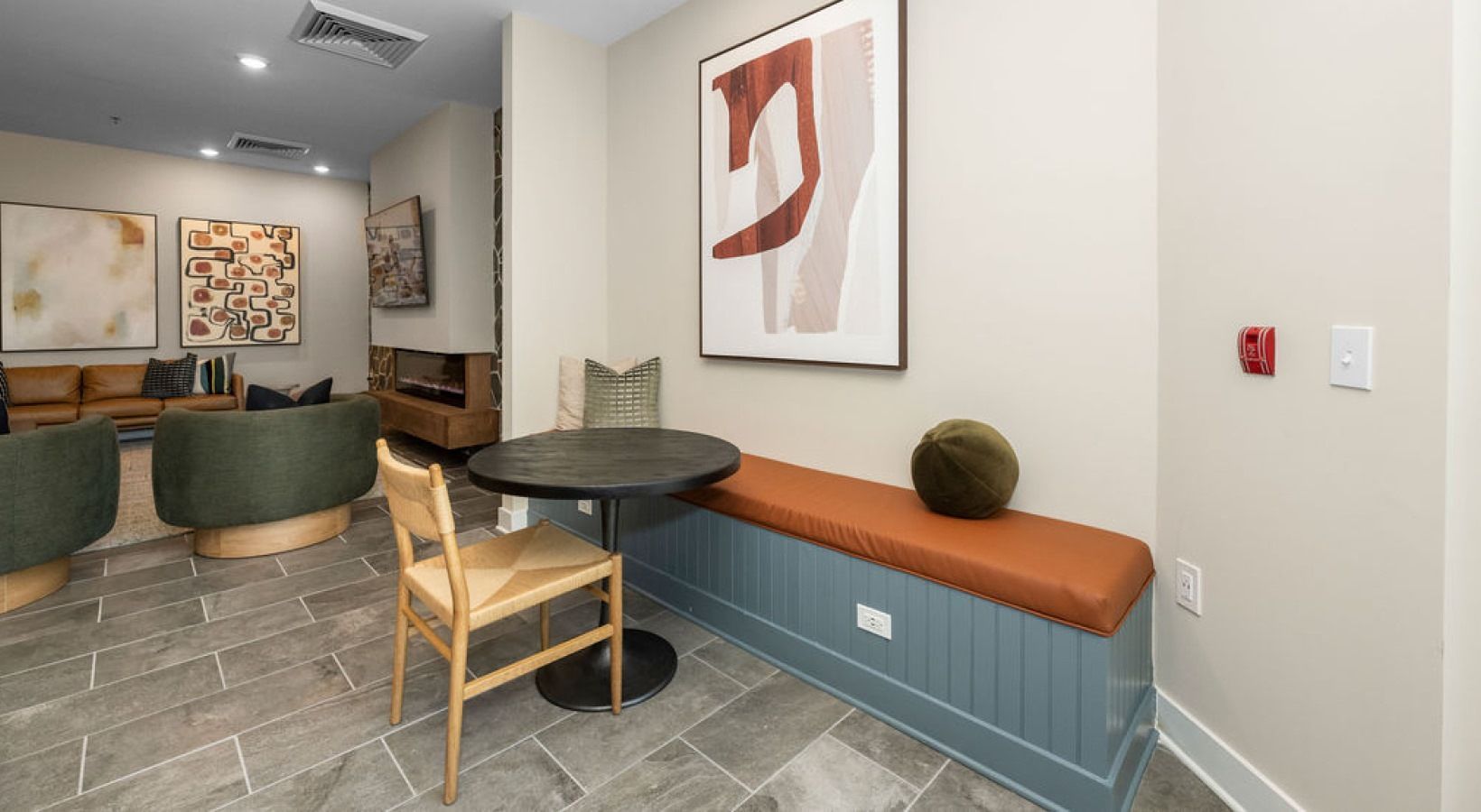 Indoor community lounge with seating, a round table, and wall art.