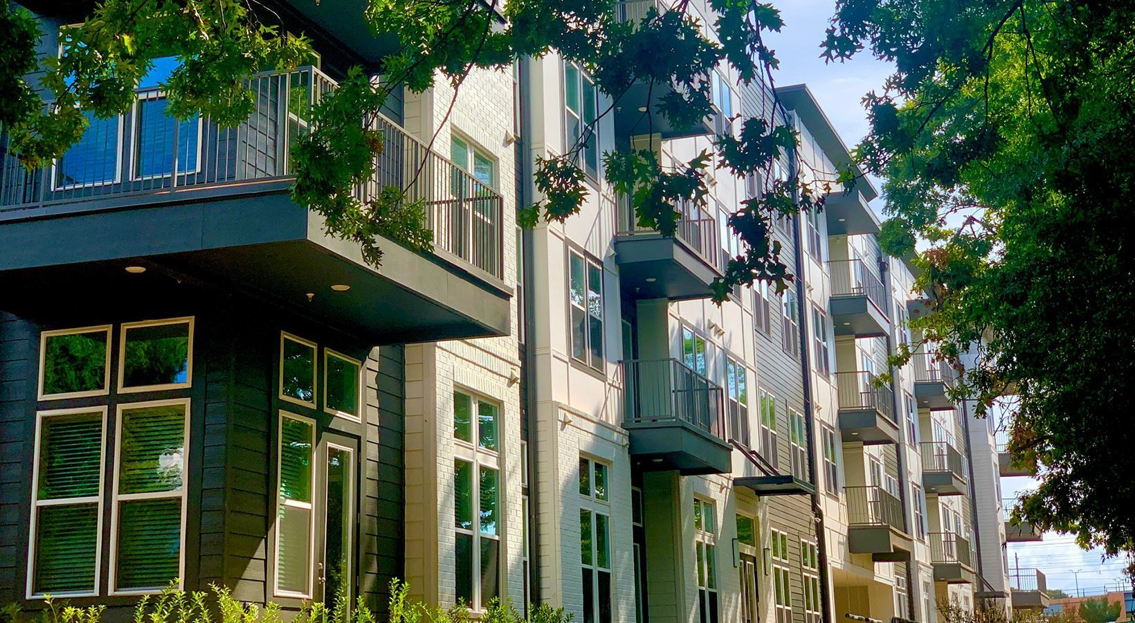 Exterior view of a modern apartment building with balconies and trees.