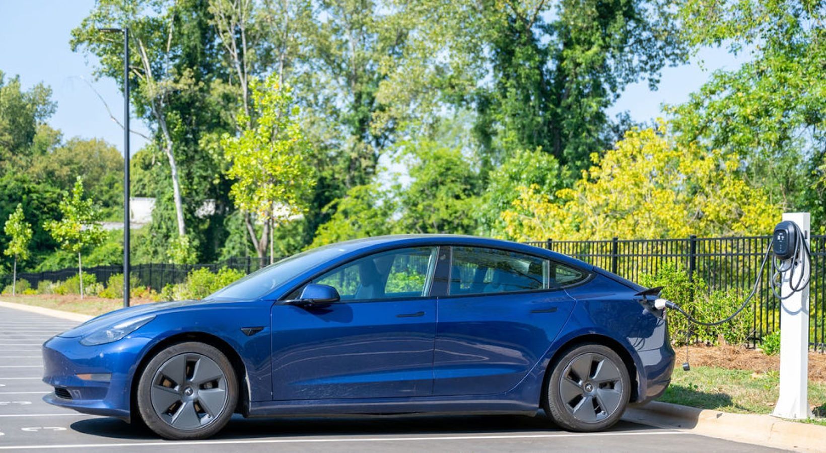 Blue electric car charging at an on-site charging station in the apartment community parking lot.
