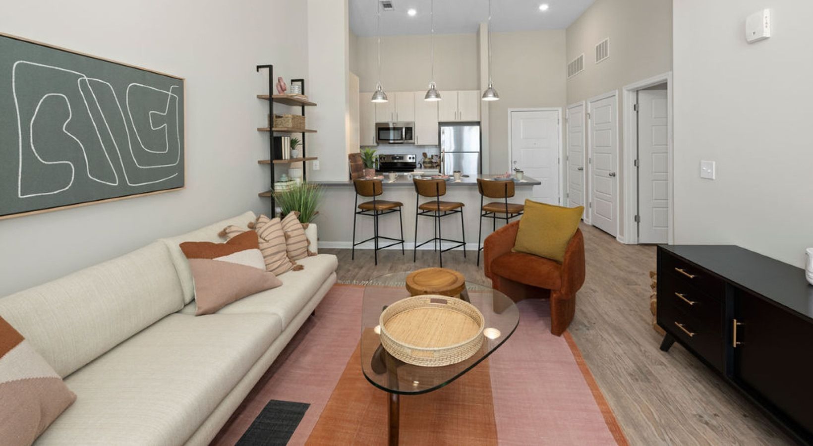 Open-concept living room with a sofa, coffee table, and a kitchen island with bar stools.