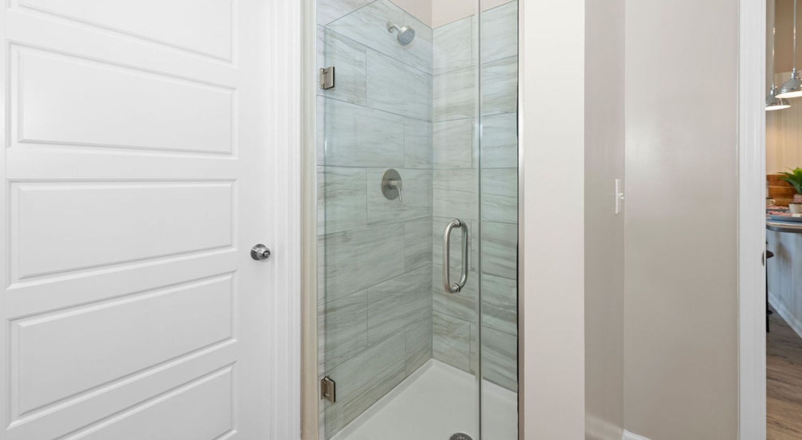 Glass shower enclosure with marble-look tiles in a modern bathroom.