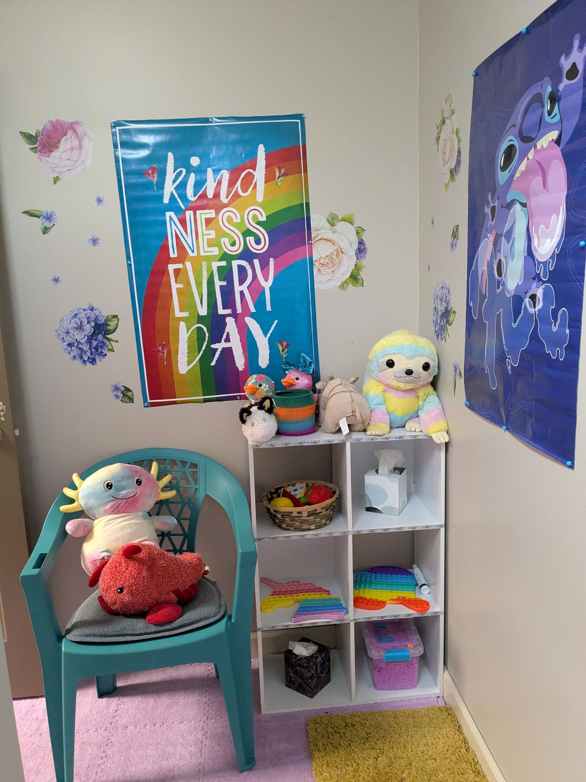 A child's play area with stuffed animals, a kindness poster, and a cube shelf.