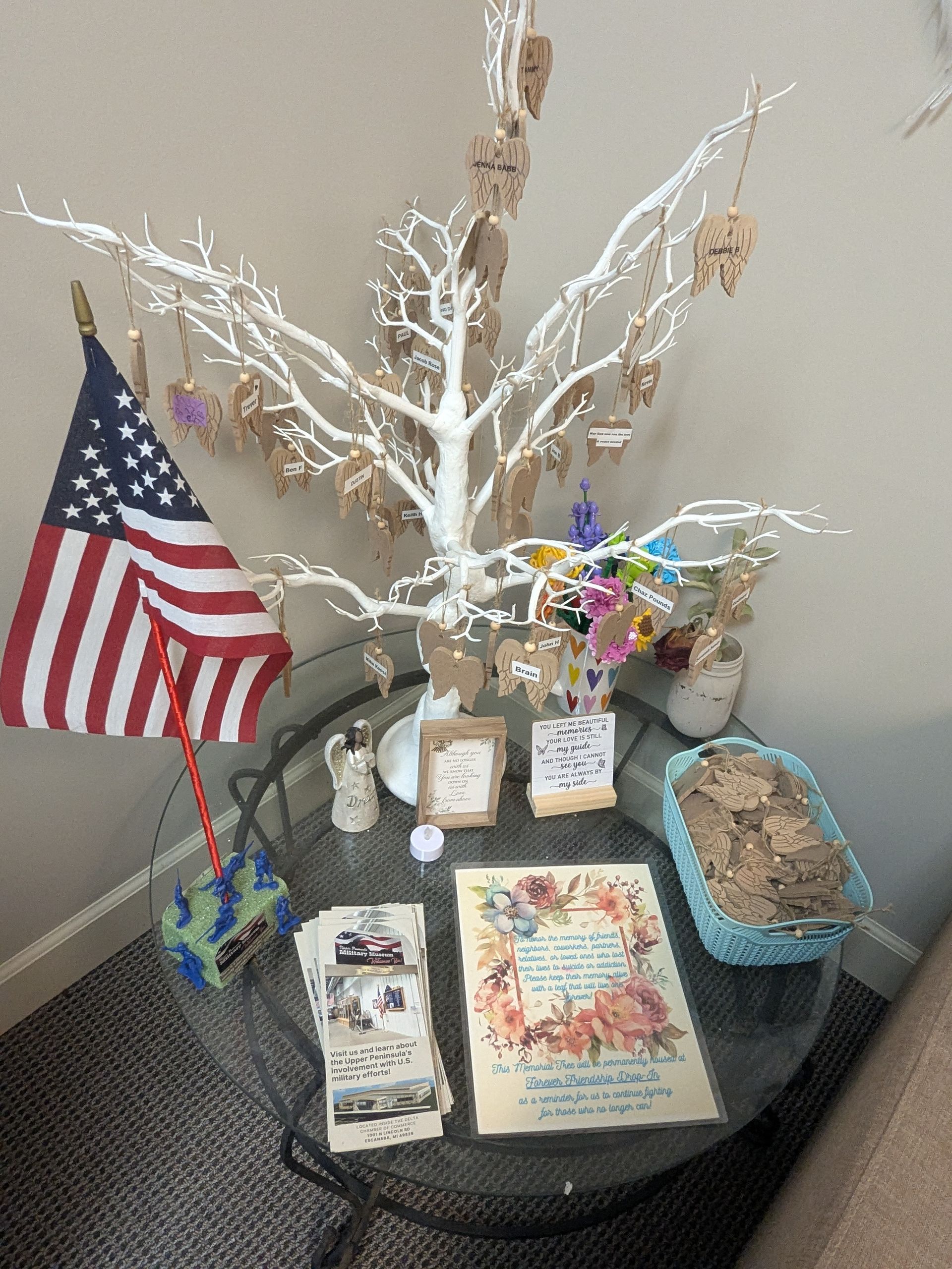 A display with an American flag, a white-branched tree with tags, and cards on a glass table.