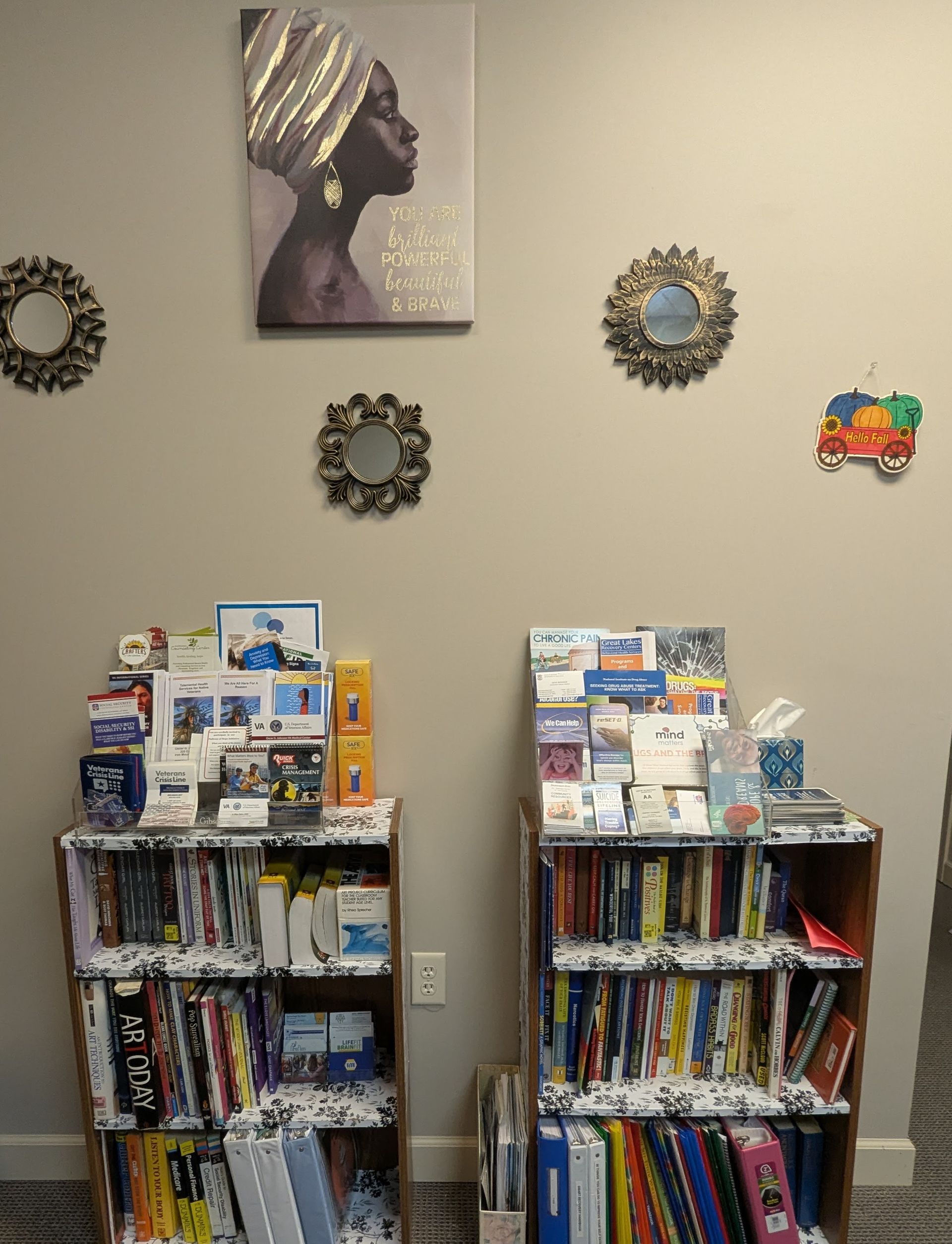 Shelves of brochures and books, wall art of a woman, mirrors, and a decorative object.