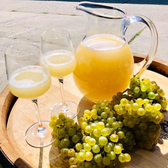 Glass of cloudy burčák on a wooden table in a Moravian wine cellar