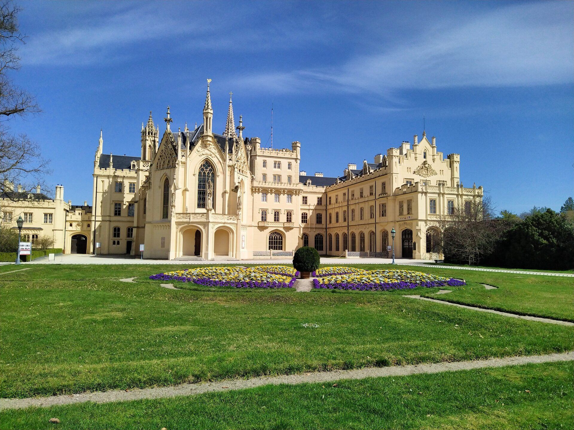 Lednice Chateau with its neo-Gothic towers and flower beds in front on a sunny day
