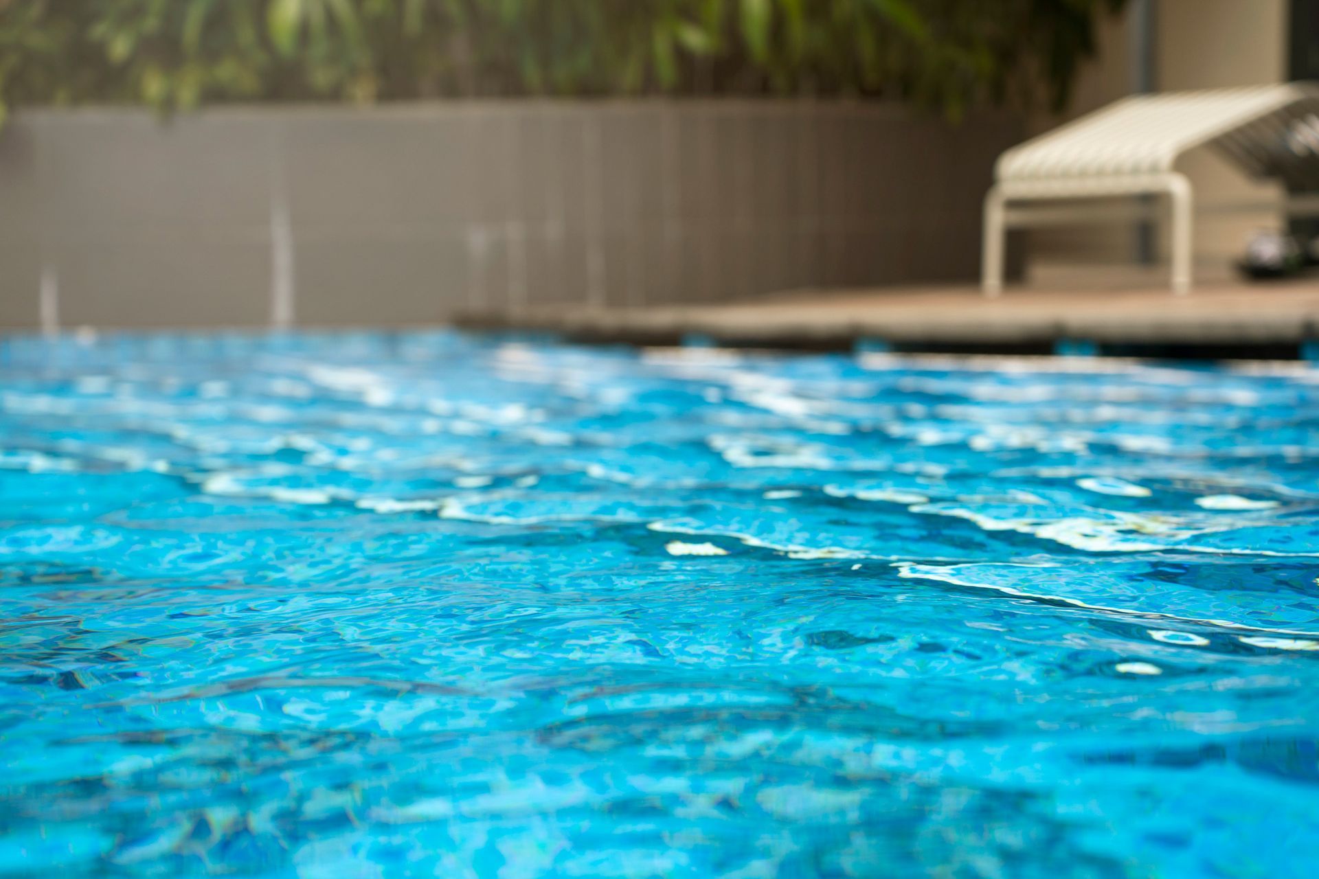 A close up of a swimming pool with a chair in the background.