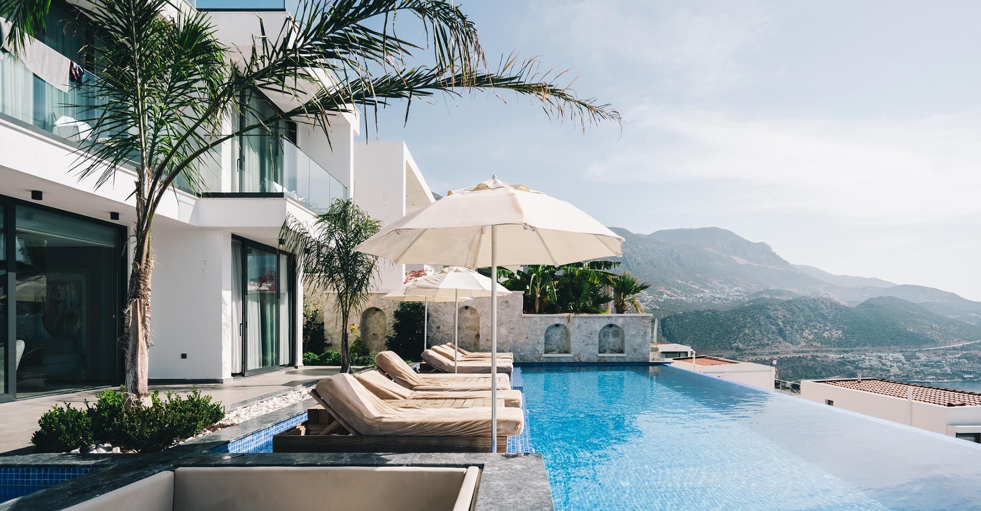 A large house with a swimming pool and umbrellas in front of it.