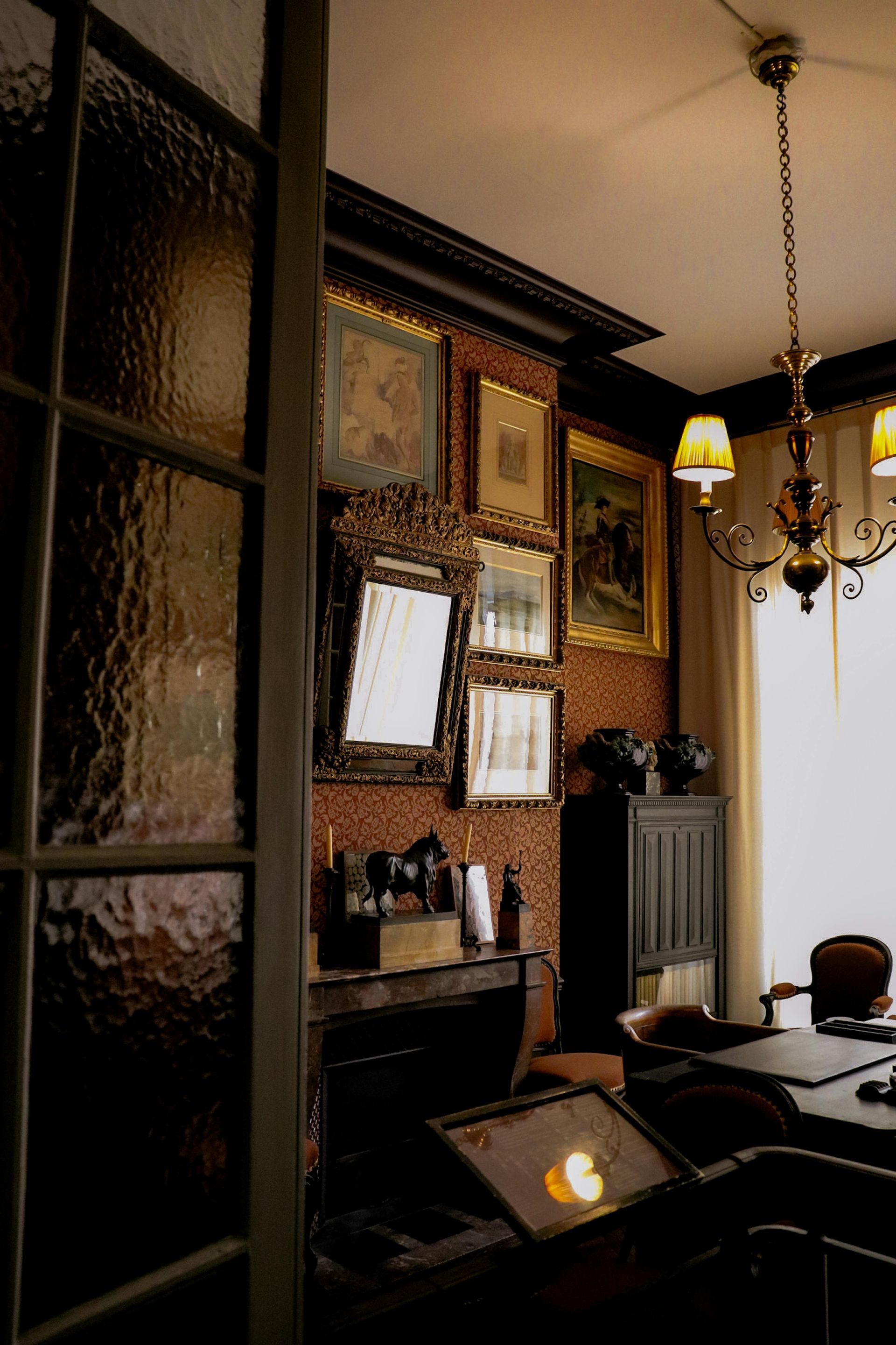 A living room with a table , chairs , mirrors and a chandelier.