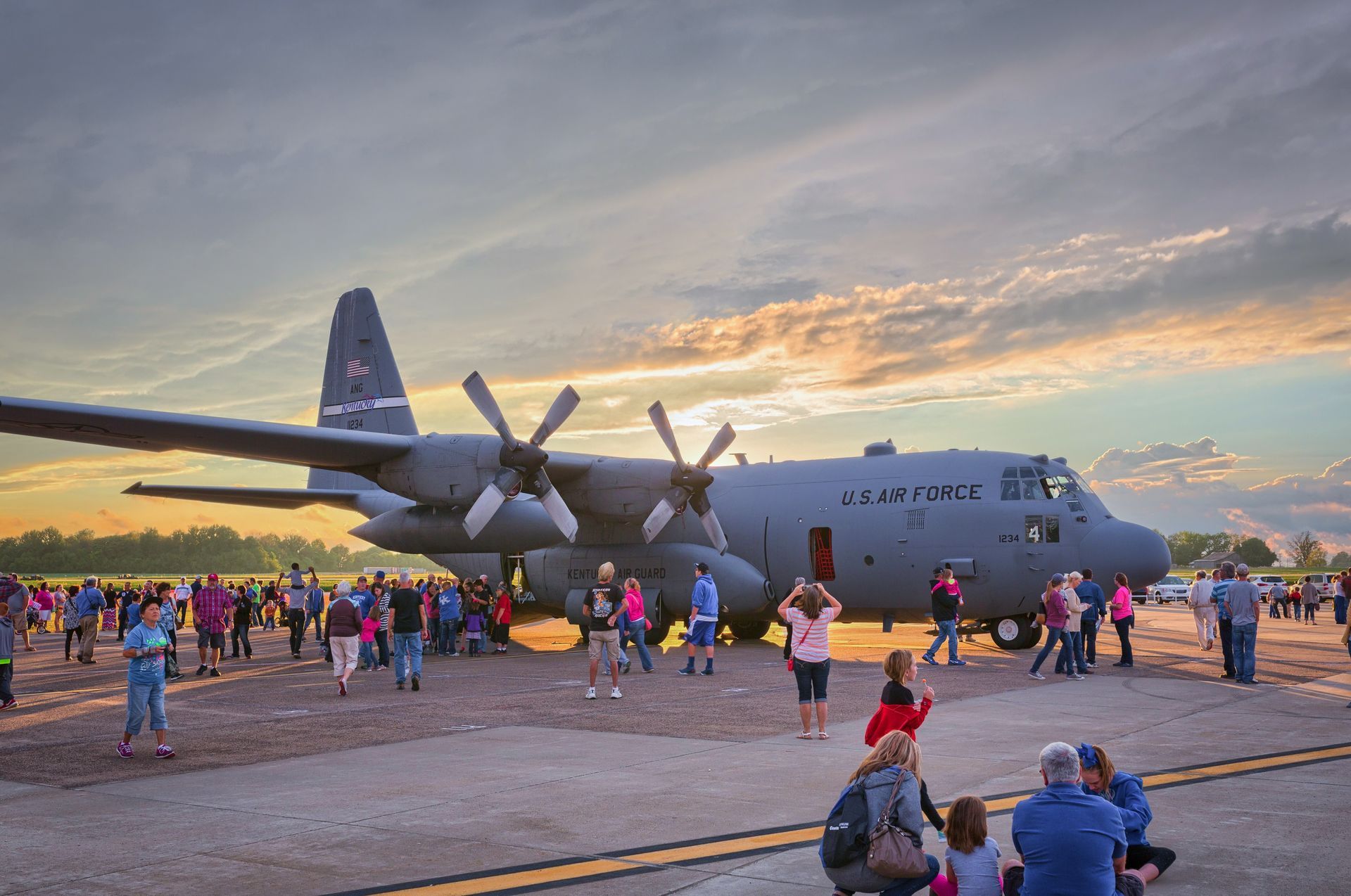A group of people are standing around a large military plane.