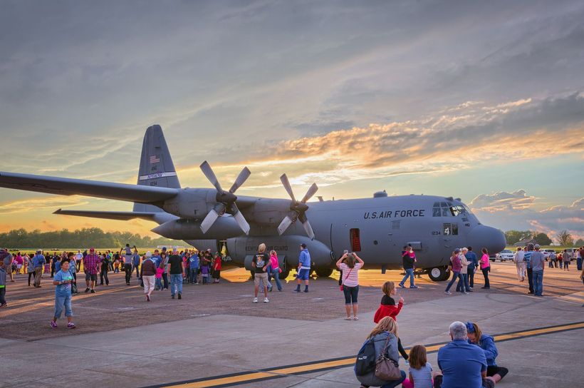 A group of people are standing around a large military plane.
