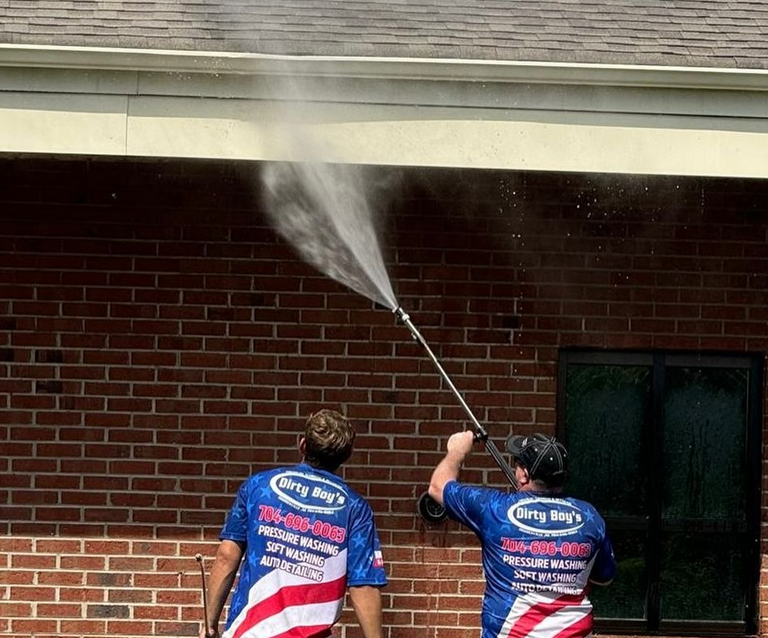 Pressure washing the wall to remove stubborn dirt and grime