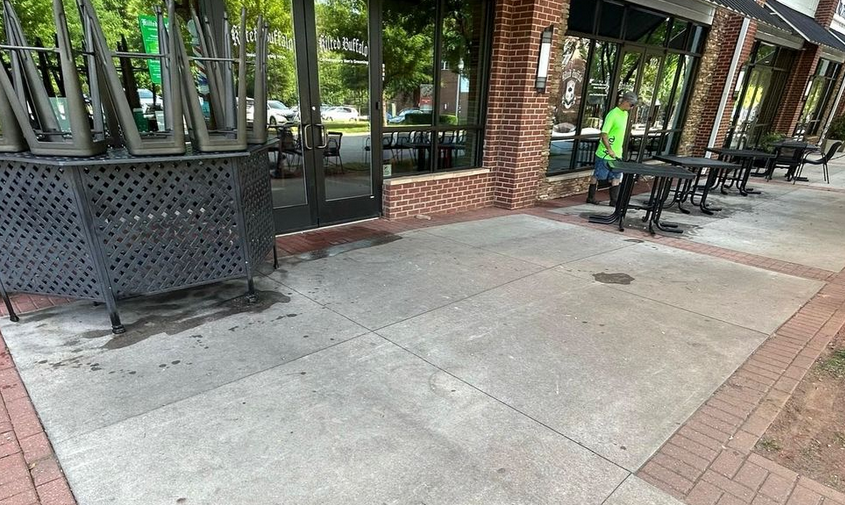 Dirty Boys crew pressure washing shopping center sidewalks in Mooresville