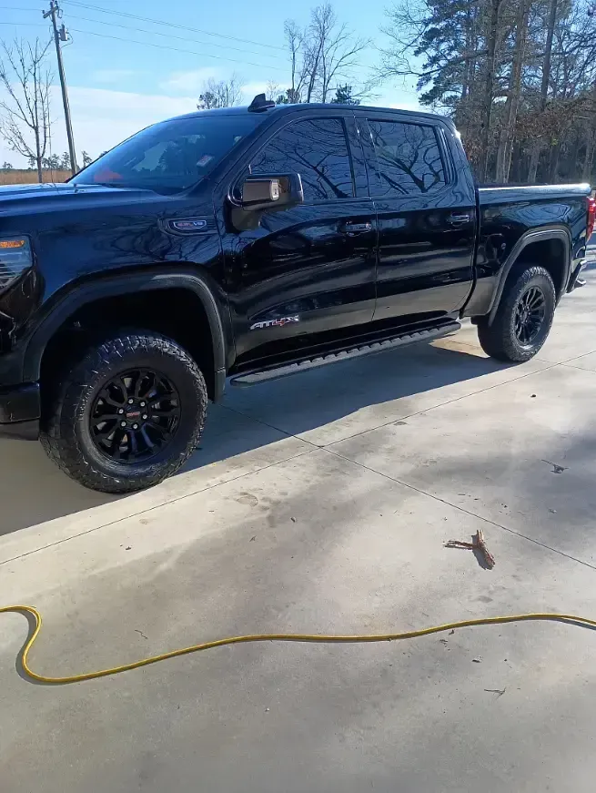 Black pickup truck with tinted windows and black wheels parked outside on a sunny day.