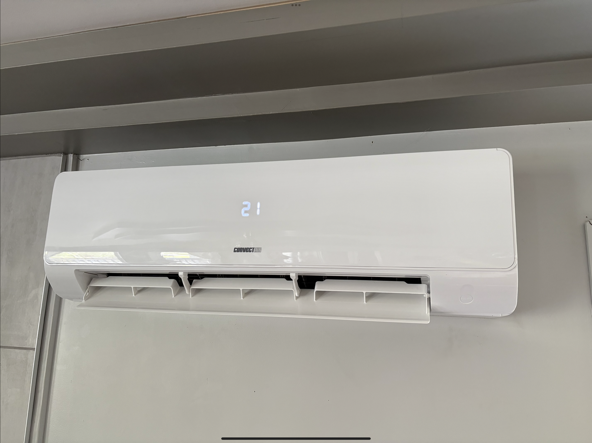 Un climatiseur split blanc fixé au mur, affichant une température de 21 degrés.